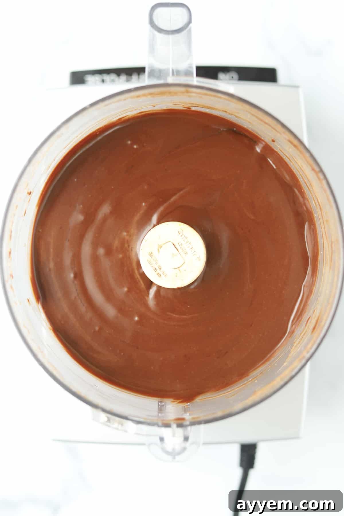 The smooth, blended homemade Nutella swirling inside a food processor bowl, indicating its creamy texture.