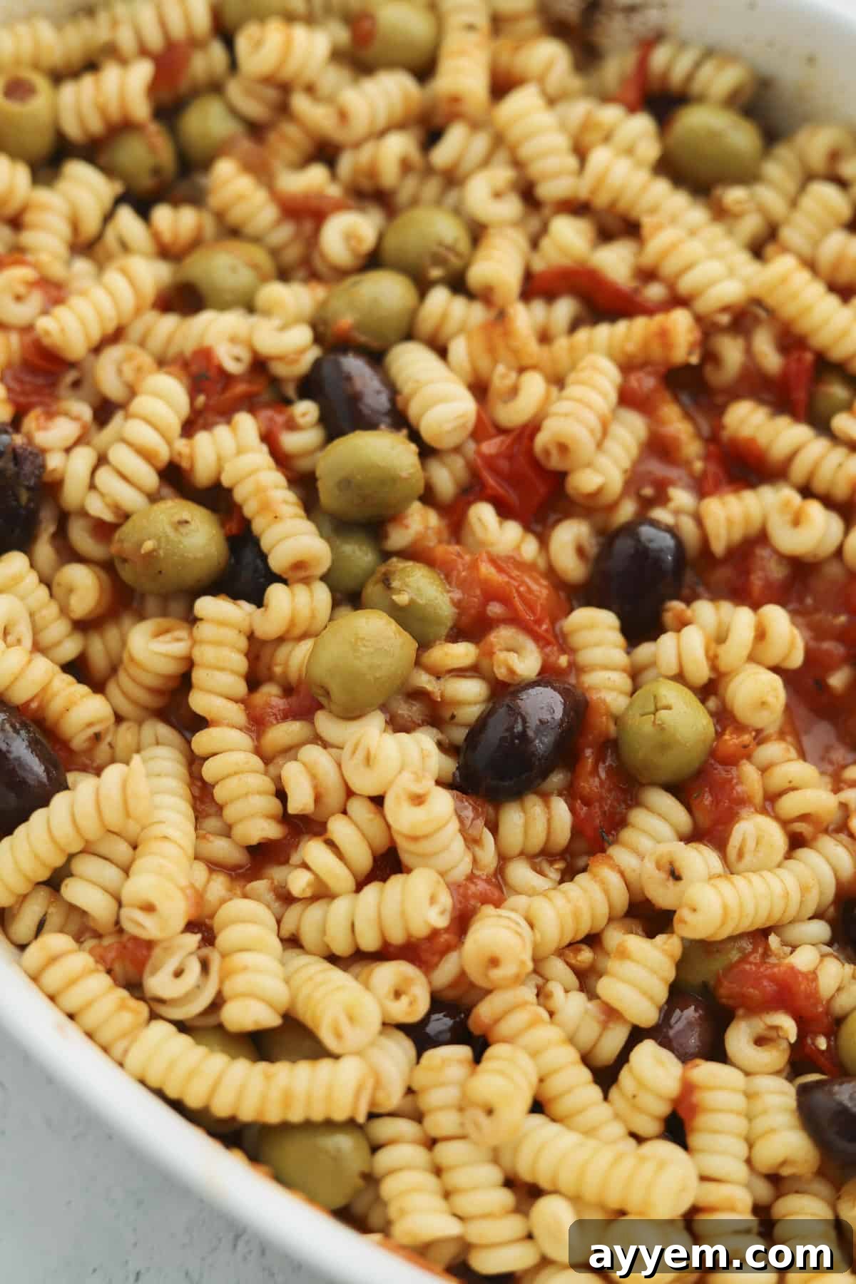 overhead of pasta in a baking dish with olives and tomatoes