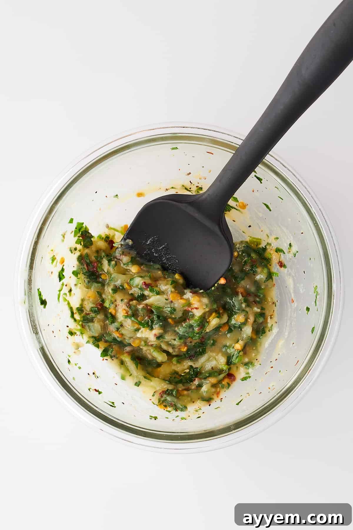 A hand mixing the cheesy garlic bread seasonings and butter in a bowl, combining the ingredients thoroughly.