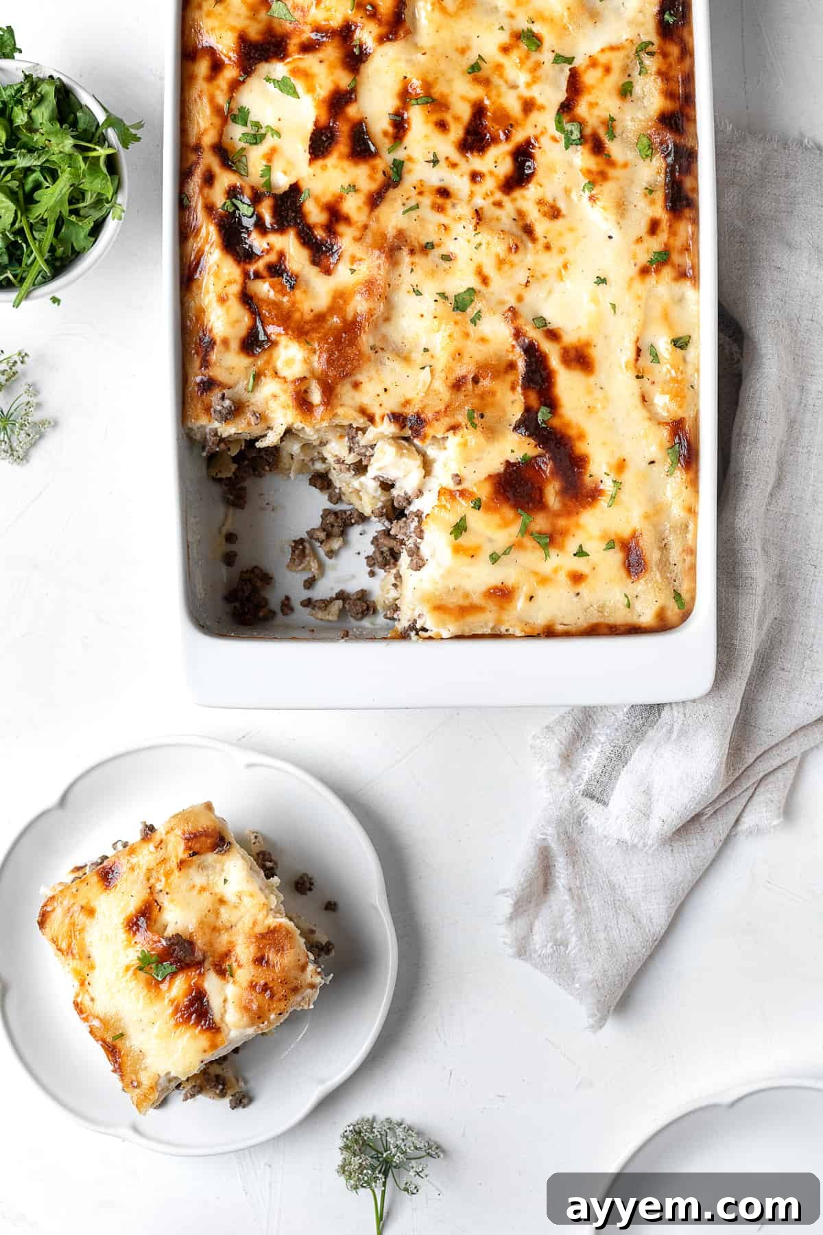 Baked Penne Pasta with Bechamel Sauce in a casserole dish with a serving missing