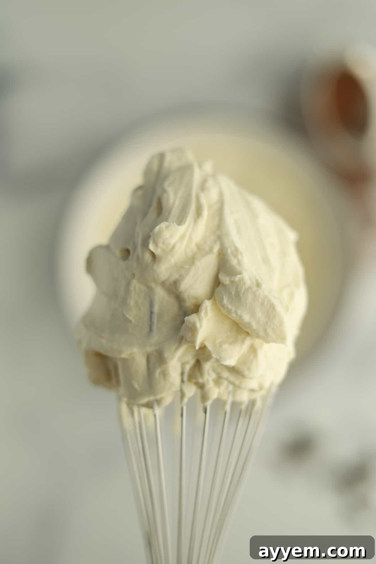 Mascarpone whip clinging to a whisk, showcasing its light and fluffy texture.