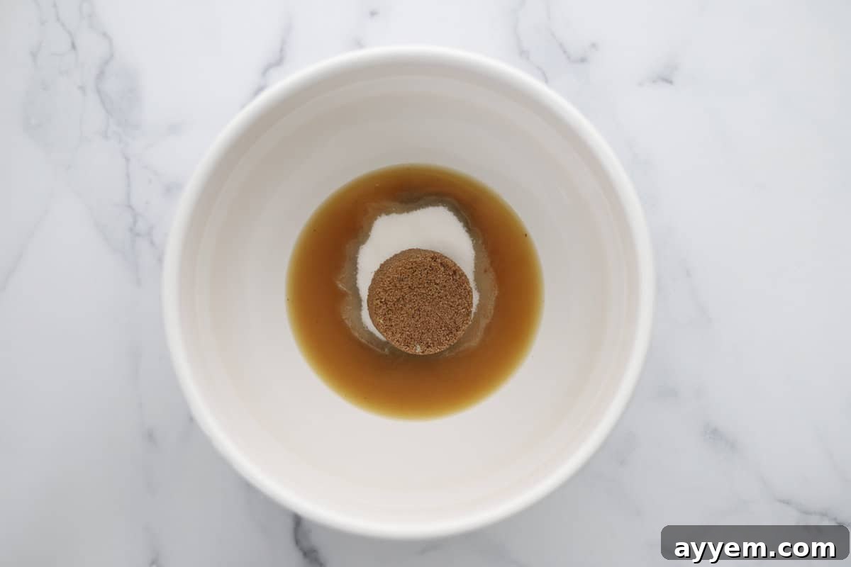 A bowl containing melted browned butter, light brown sugar, and granulated sugar, ready for mixing.