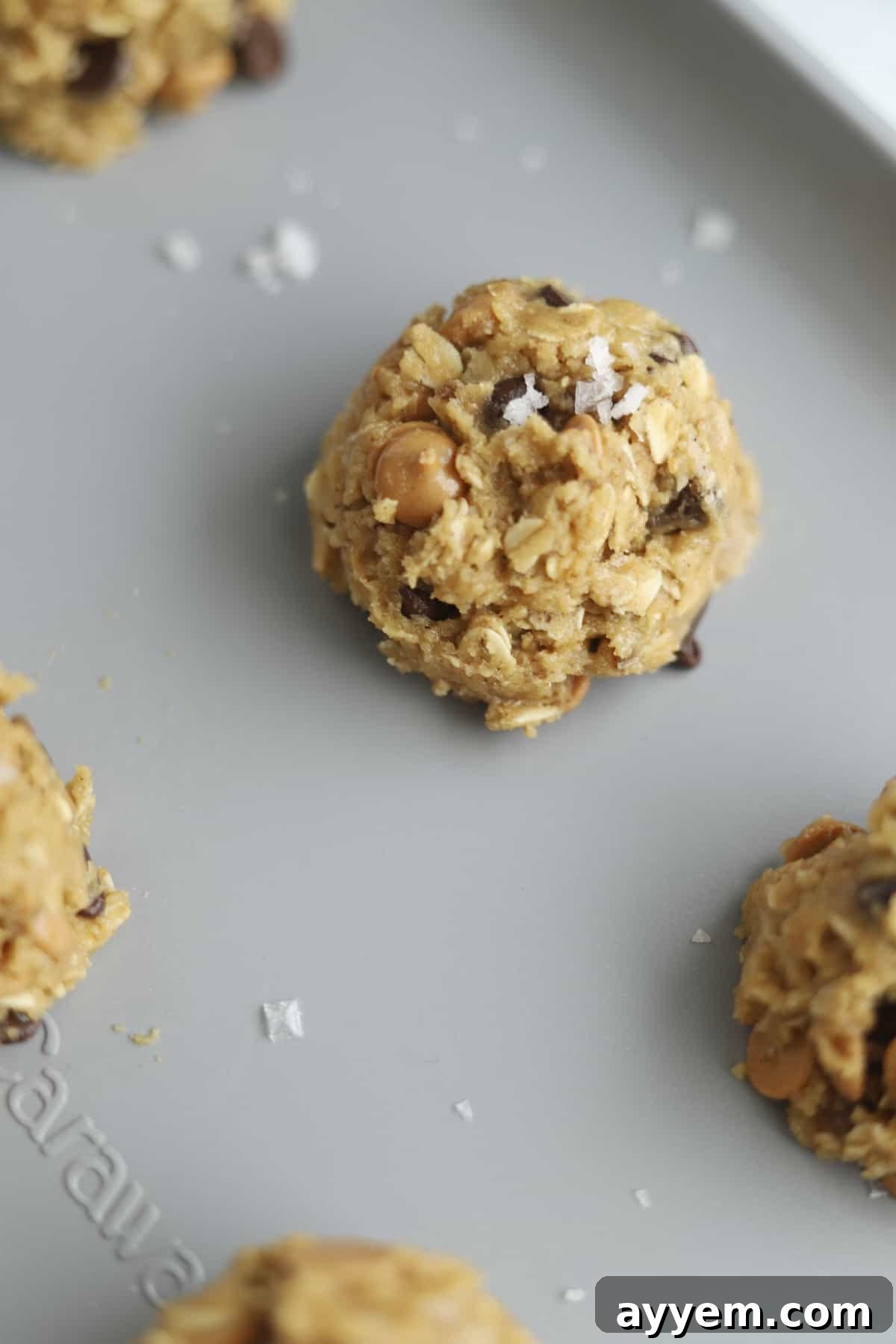 A perfectly portioned ball of Crumbl Cookies Mom's Recipe copycat cookie dough, ready for baking on a parchment-lined sheet.