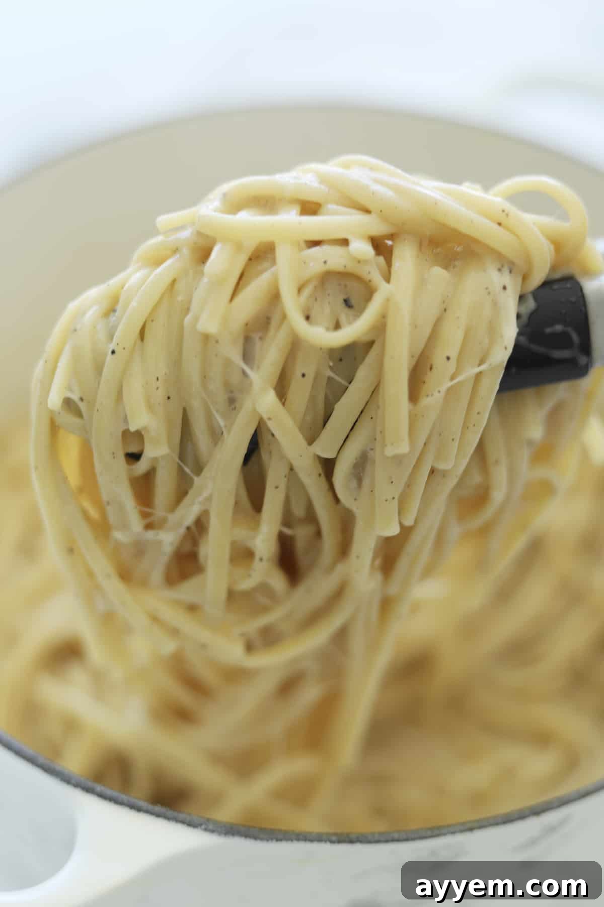 Ultimate One Pot Cacio e Pepe 5 Tongs gracefully lifting a generous helping of creamy One Pot Cacio e Pepe from the pan, ready for serving.