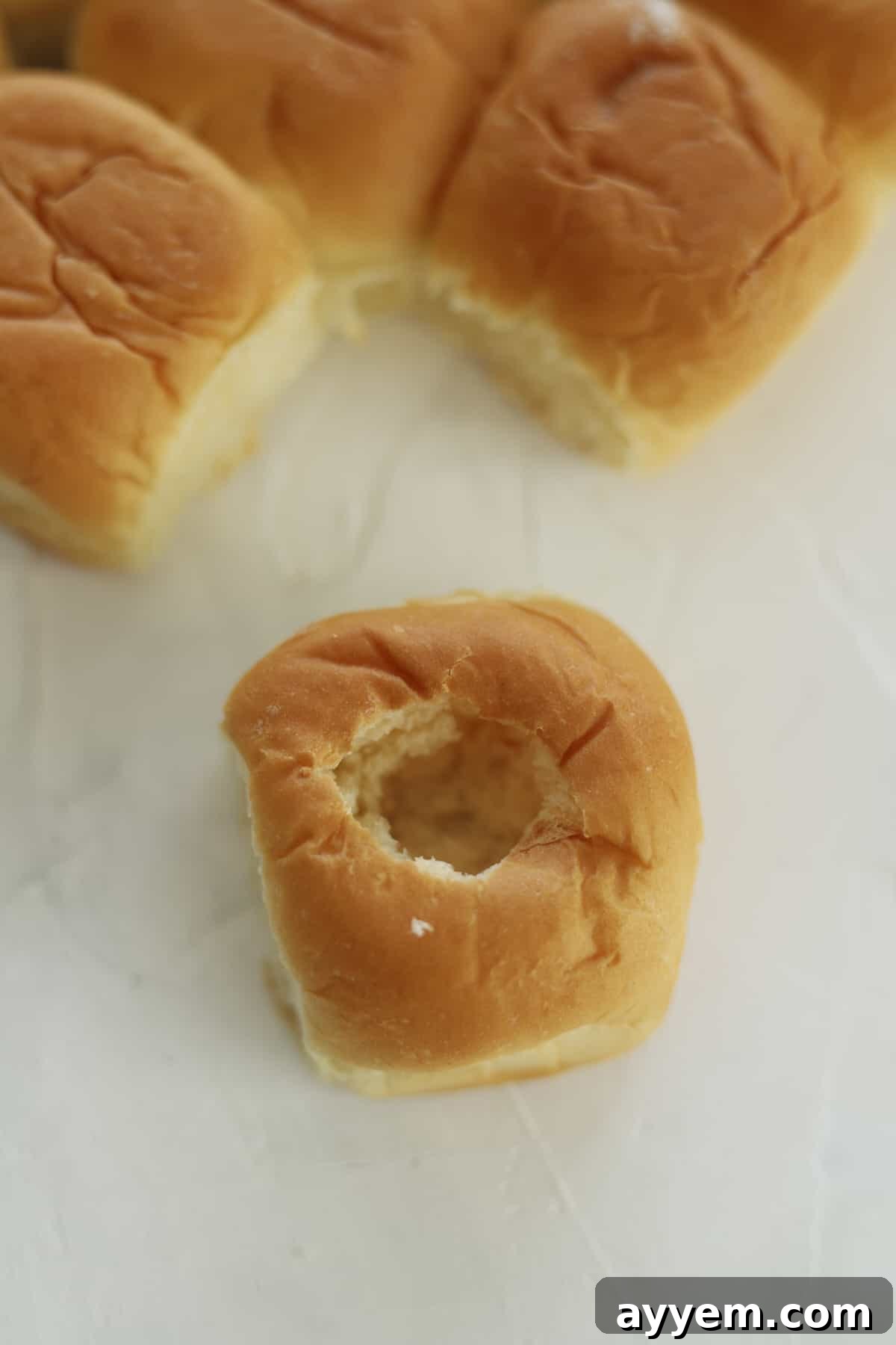Hawaiian rolls, one with a hole poked into the center