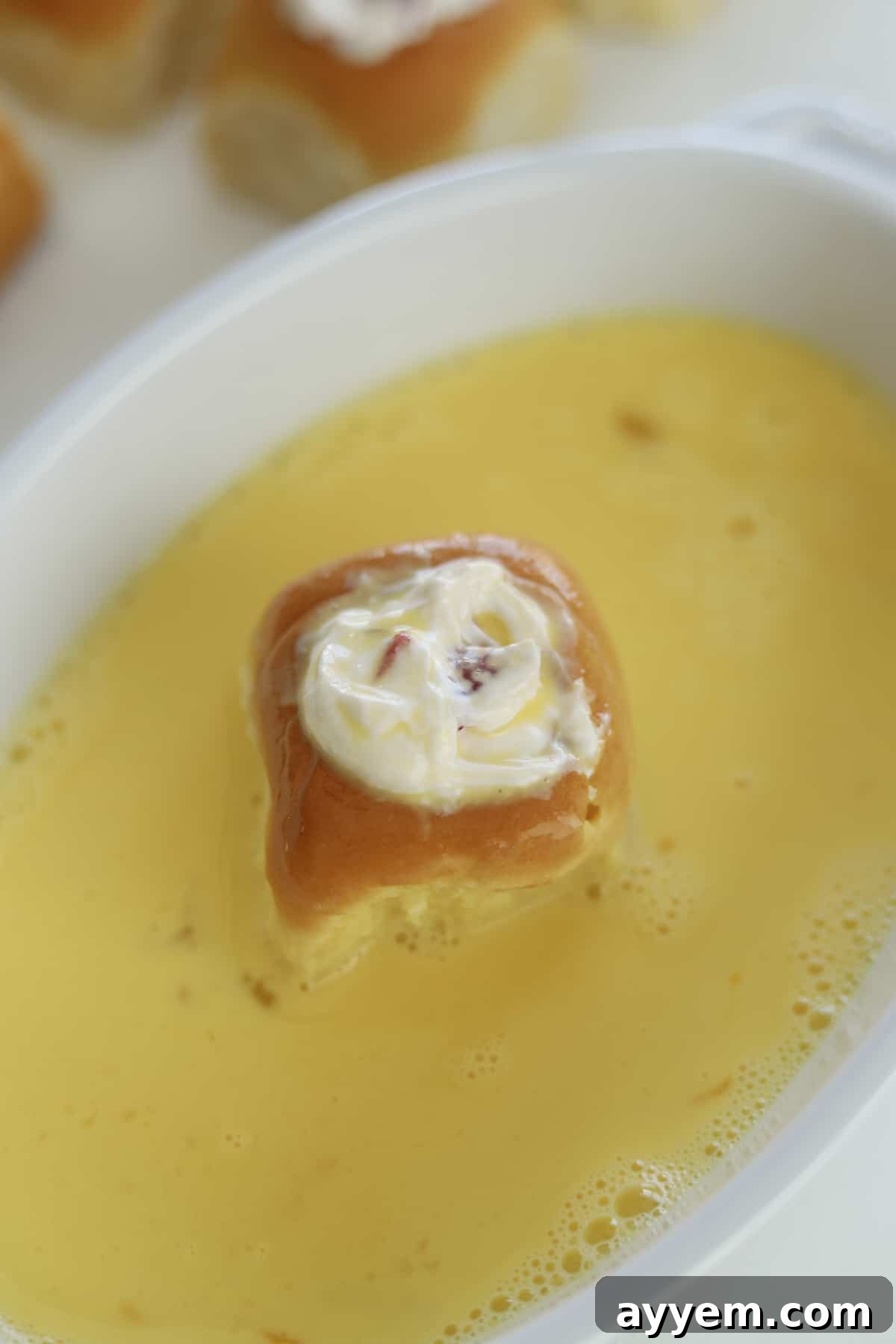 a strawberry cream cheese stuffed Hawaiian roll in an egg wash