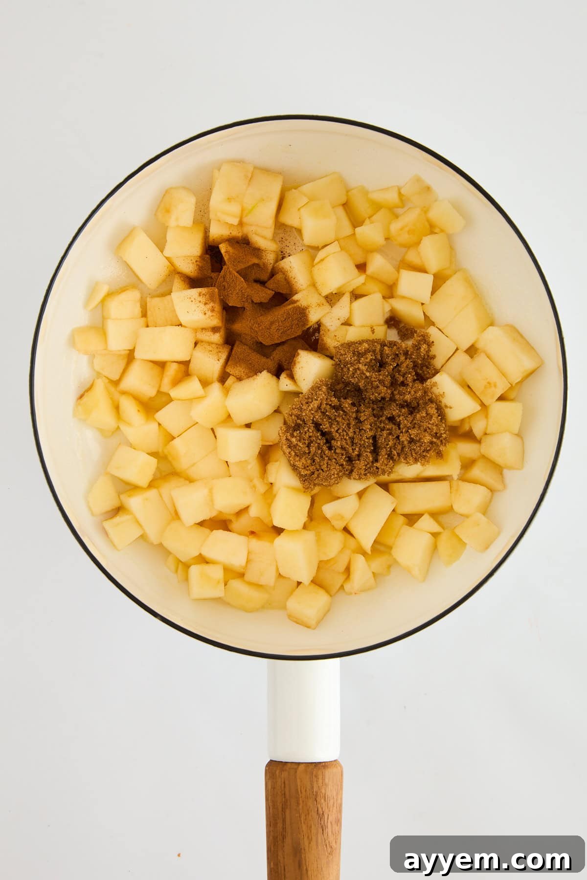 Oats and milk added to the pot with the caramelized apples, simmering to create creamy oatmeal.