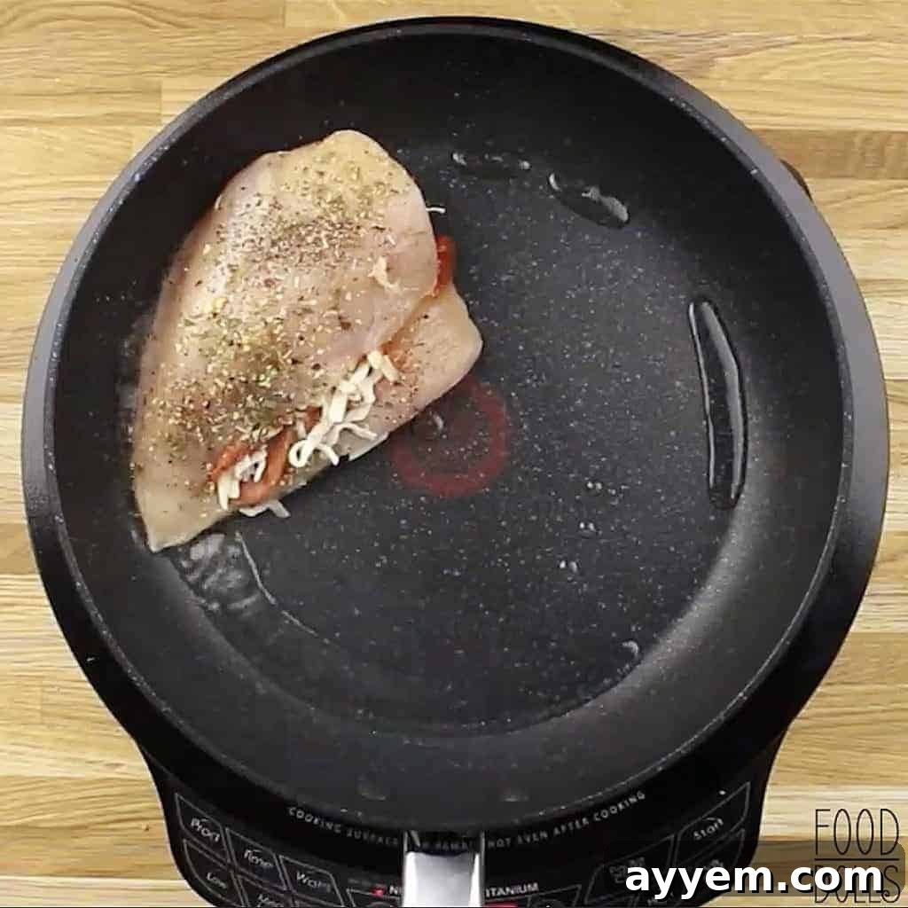 Raw cheesy pizza stuffed chicken breast in a skillet.