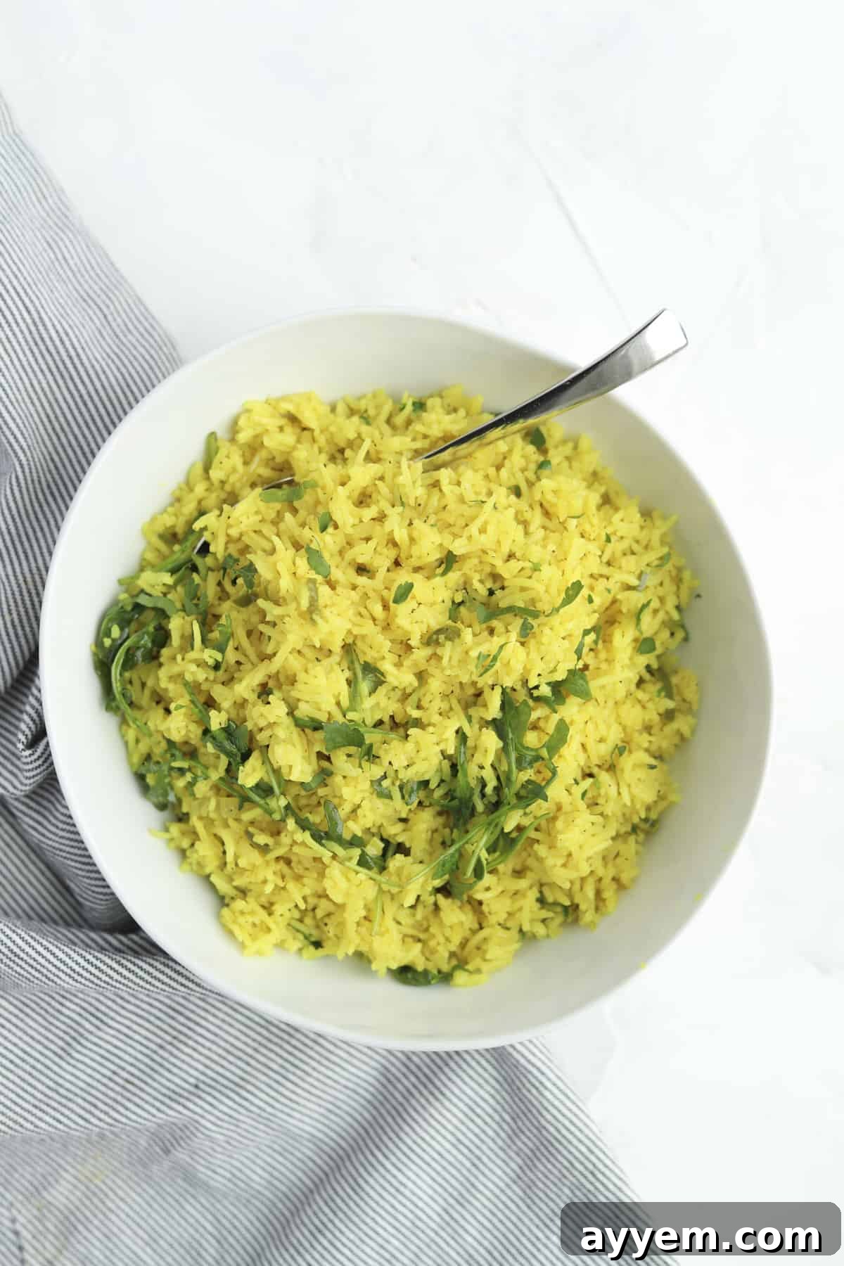 A bowl of fresh Coconut Turmeric Rice garnished with vibrant herbs