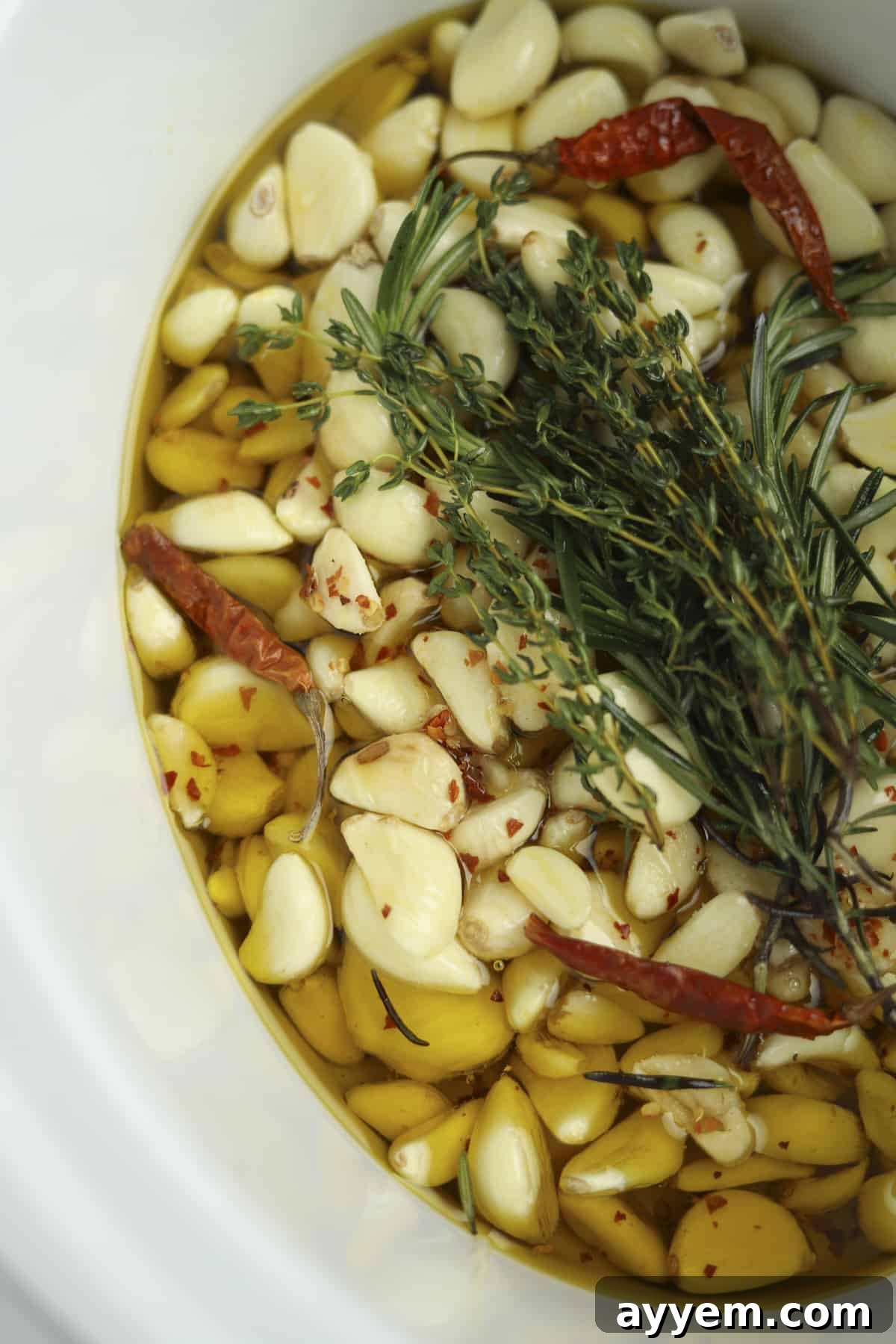 Close-up overhead shot of cooked slow cooker spicy honey garlic confit with herbs.