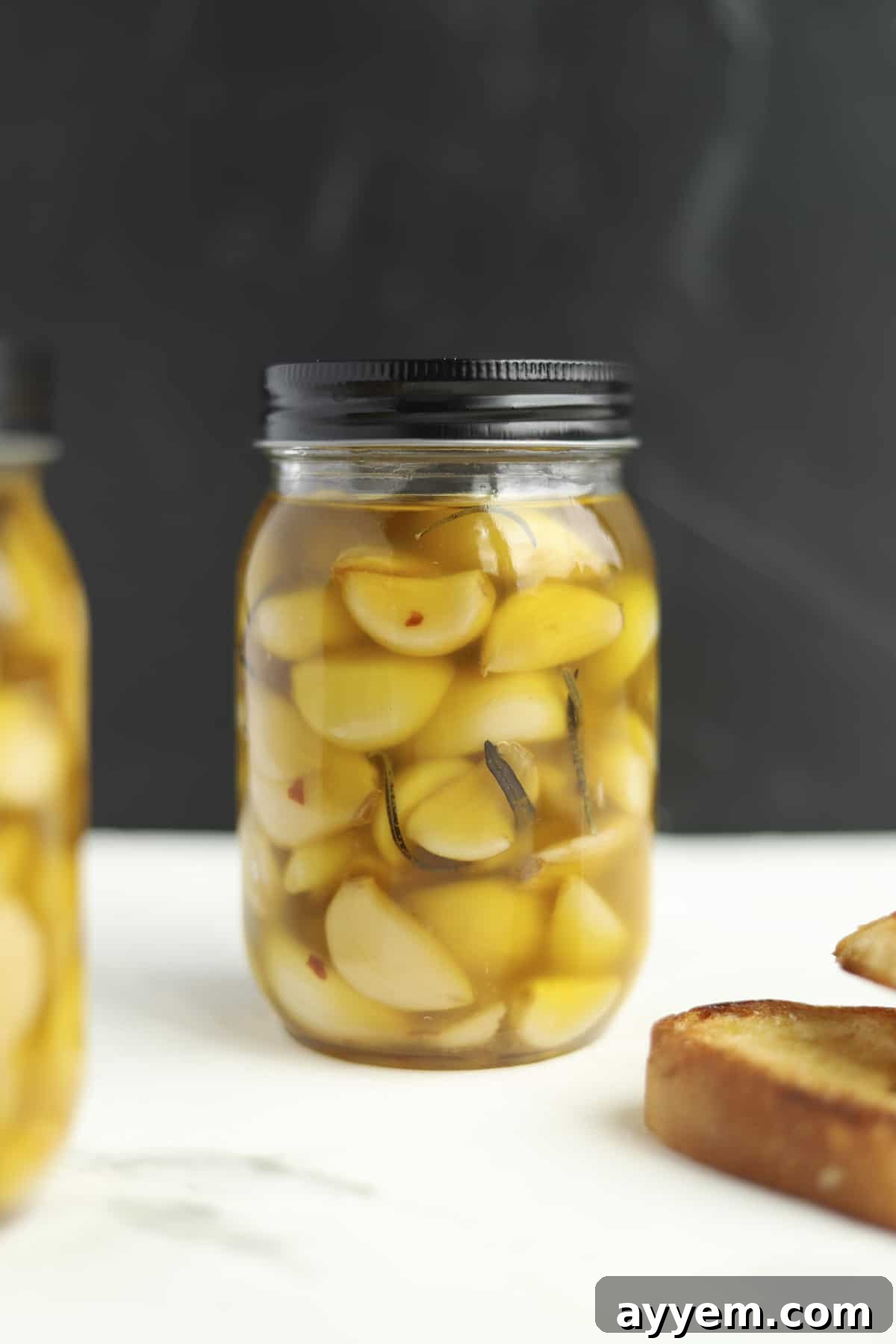 Mason jar filled with slow cooker spicy honey garlic confit, ready for storage.