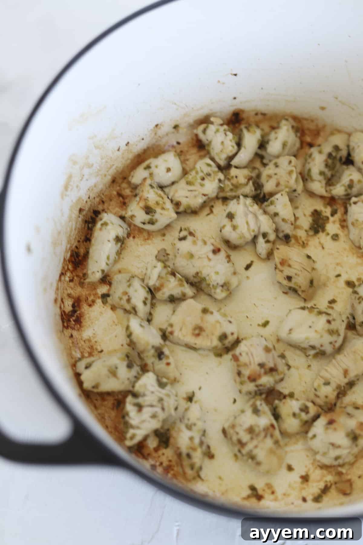 Seasoned chicken pieces searing in a deep pot, ready to be combined with other ingredients.