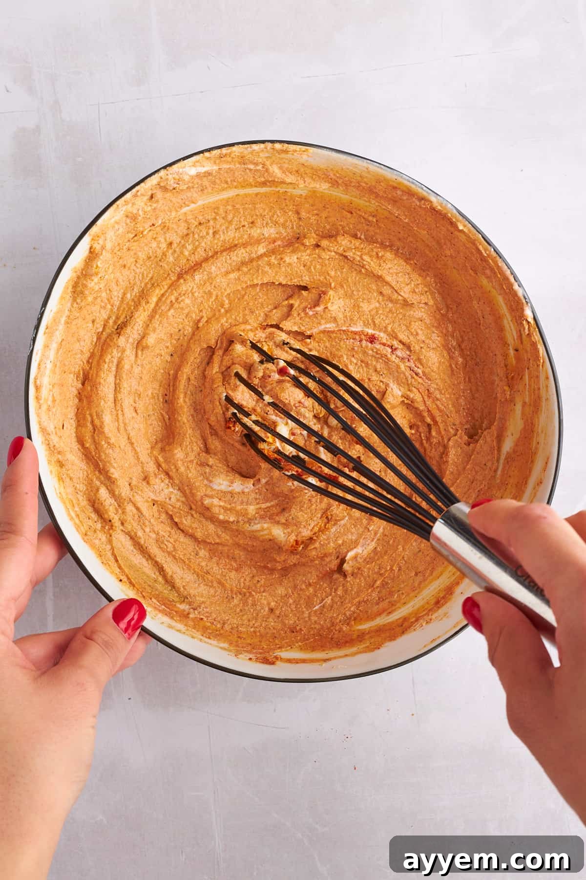 Shawarma marinade being whisked to a smooth consistency in a mixing bowl, showcasing its rich color and inviting texture.