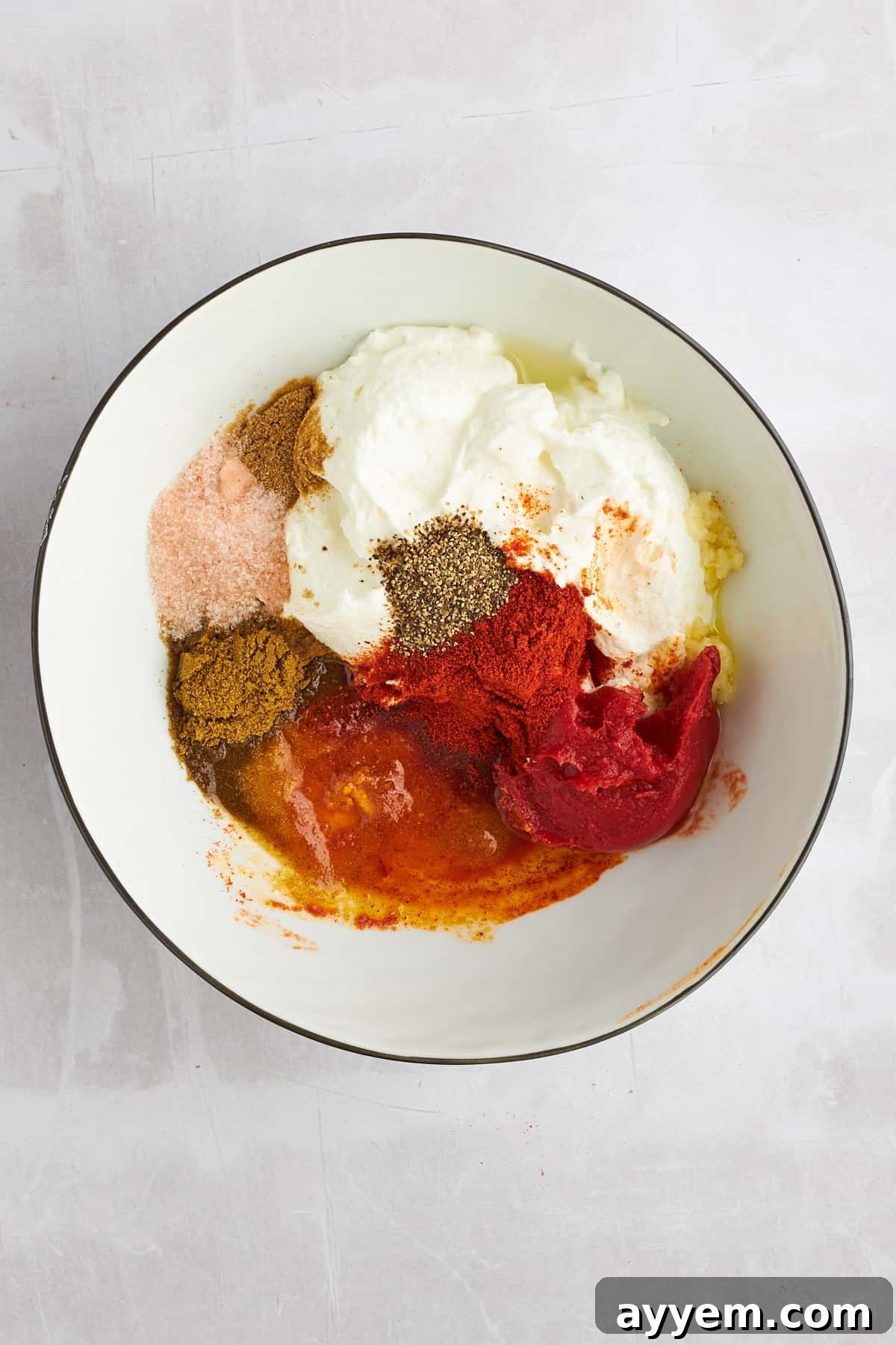 All the vibrant shawarma marinade ingredients, including fresh lemon, tomato paste, and a selection of spices, neatly laid out in a bowl before mixing.