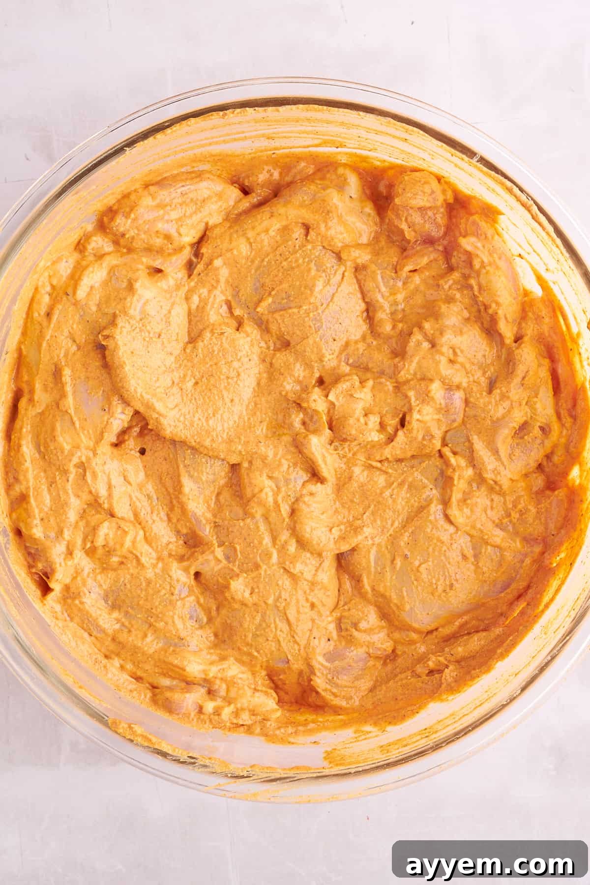 Raw chicken shawarma pieces thoroughly coated in a rich, reddish marinade, glistening and ready for the next step of cooking.