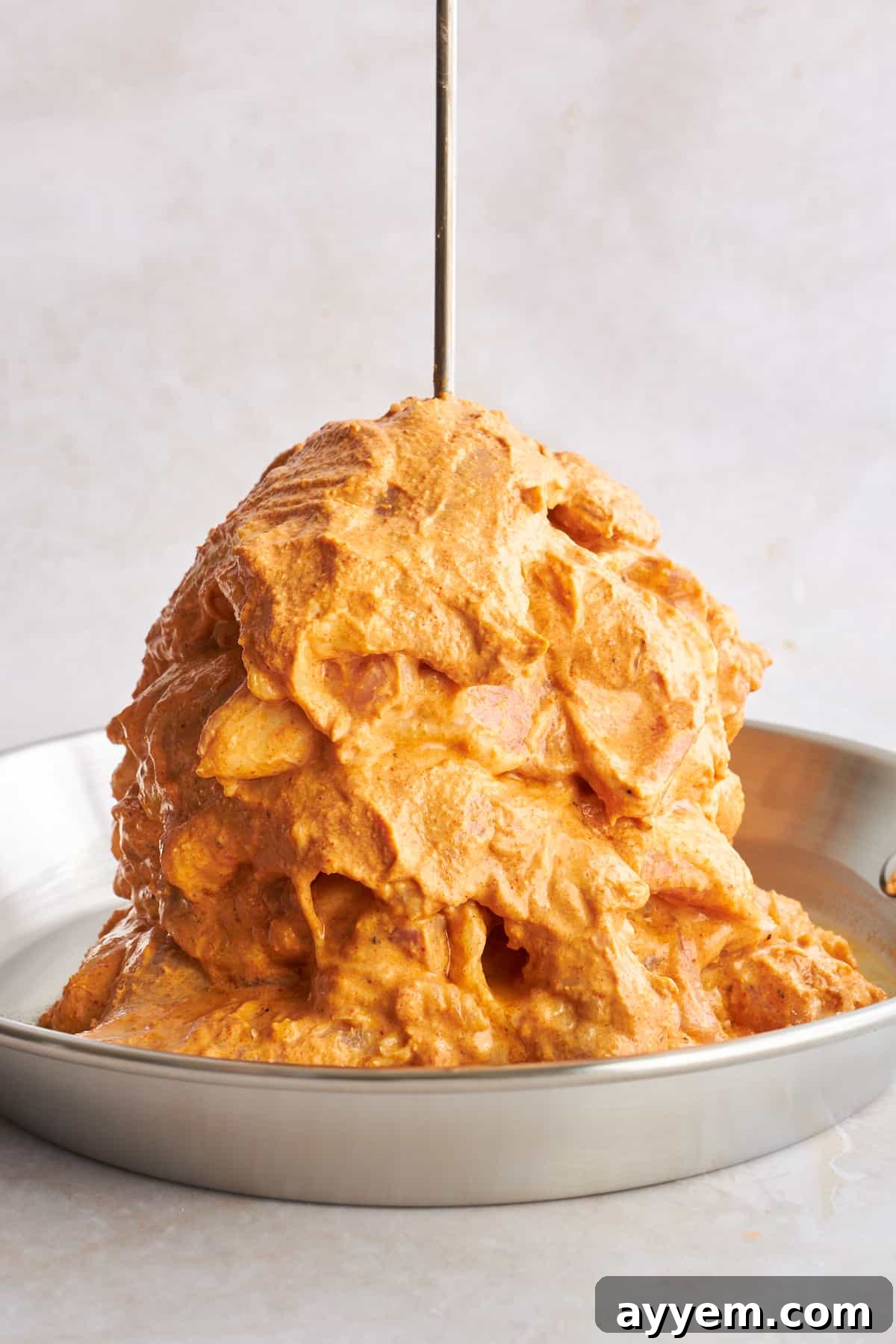 Raw chicken shawarma stacked vertically on a home-style spit, expertly arranged and ready for oven roasting, promising juicy results.