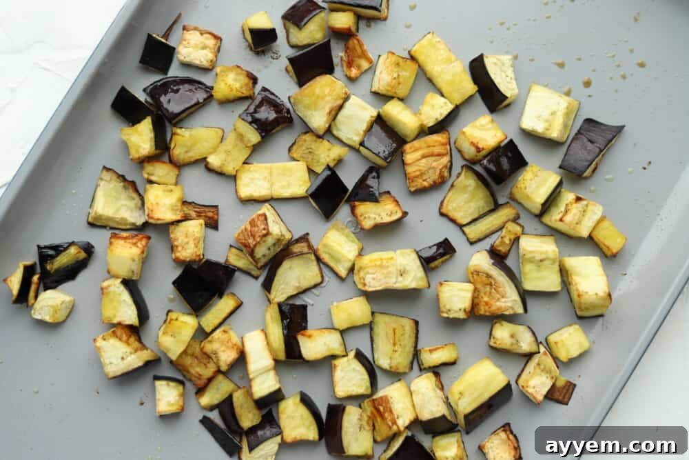 Roasted eggplant on a baking sheet, seasoned and ready for a roasted eggplant salad