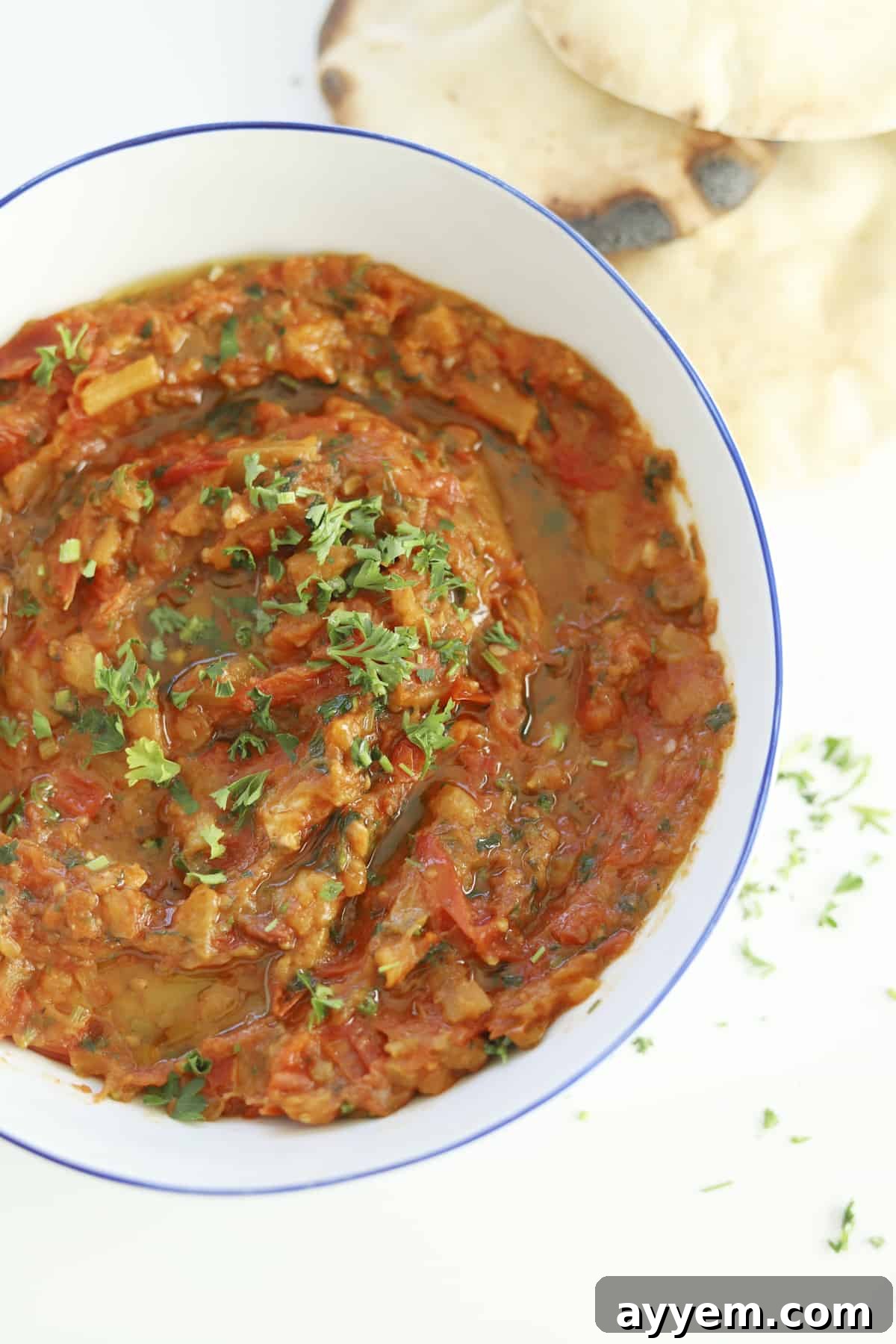 Moroccan Zaalouk served in a decorative bowl, topped with a generous sprinkle of fresh herbs and a drizzle of olive oil.