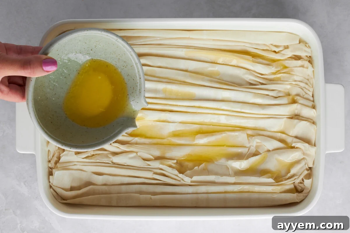 Melted butter being poured over crinkled phyllo dough.