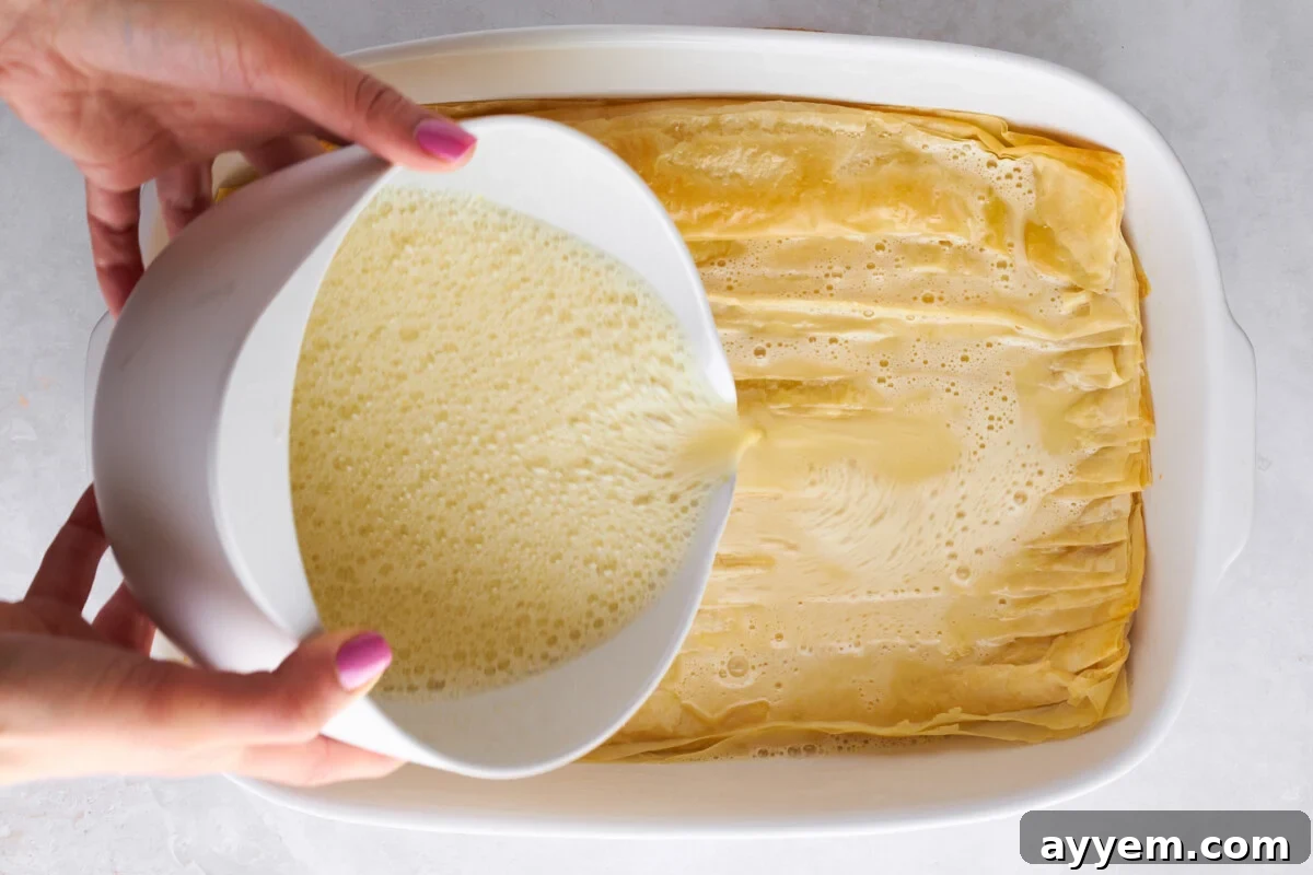 Egg mixture being poured over baked crinkled phyllo.