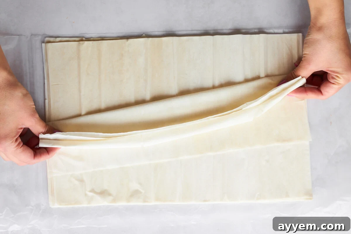 Raw phyllo dough being folded accordion-style.