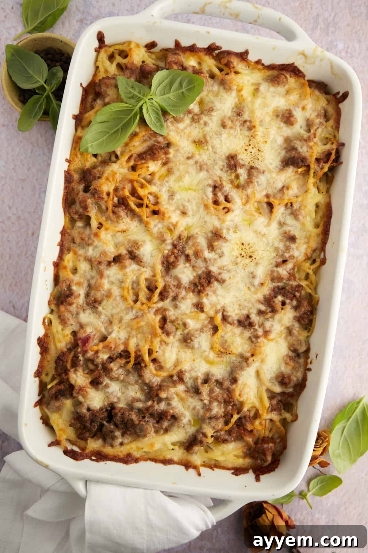 A generously sized casserole dish brimming with easy baked million dollar spaghetti, topped with golden brown, bubbly cheese.
