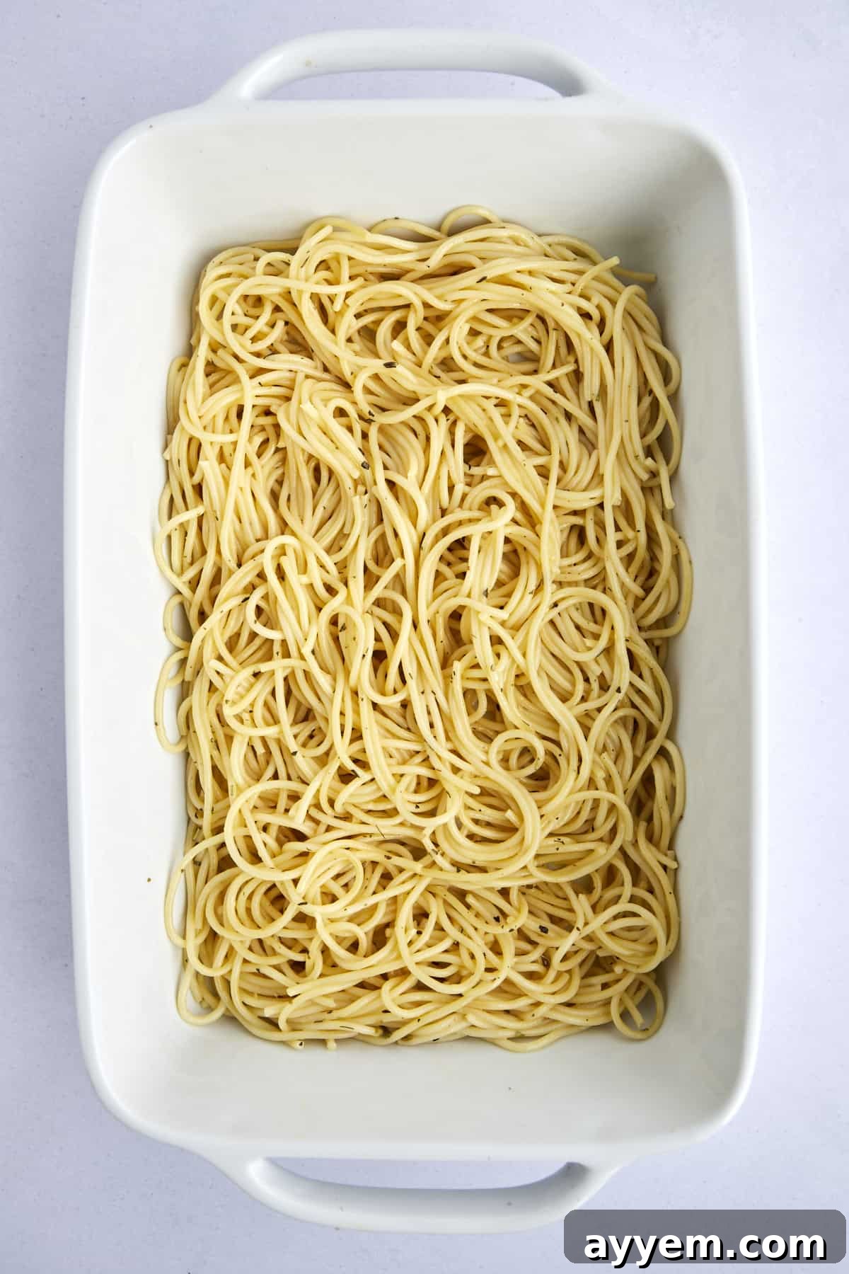 Cooked spaghetti noodles carefully laid out in the bottom of a casserole dish, ready for the next delicious layer.