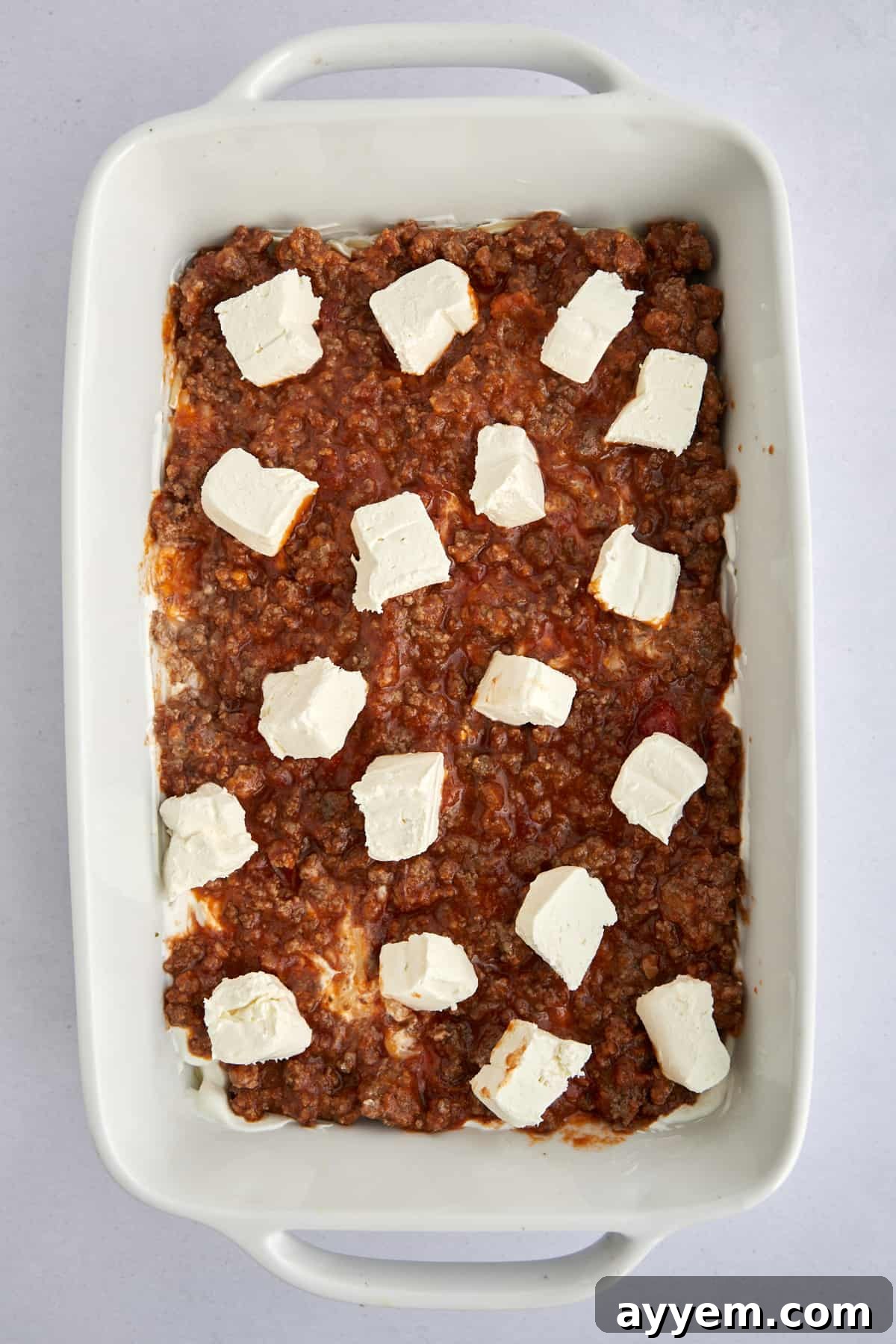 An unbaked Million Dollar Spaghetti casserole, beautifully layered and topped with generous chunks of mozzarella cheese, ready for the oven.
