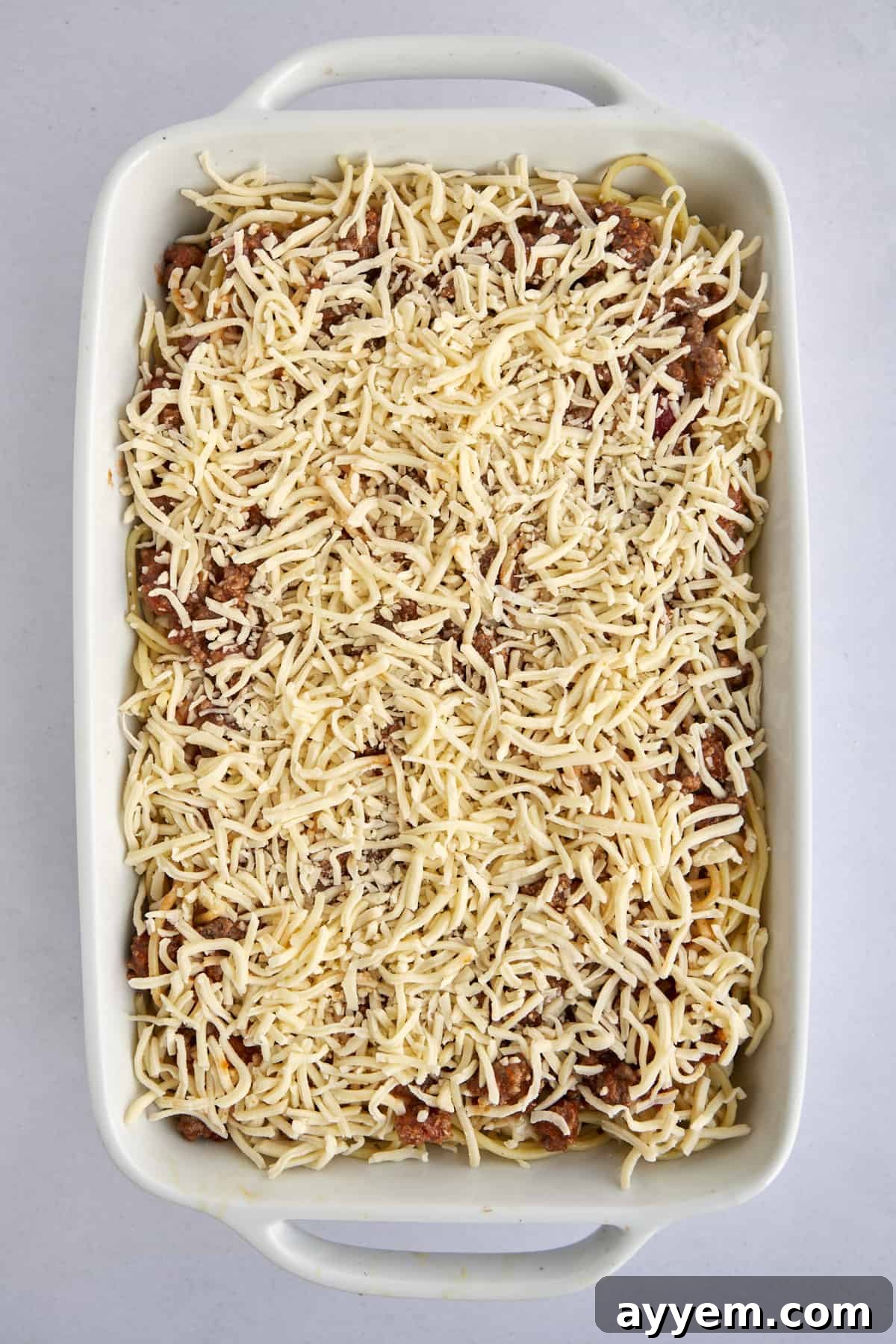 A complete unbaked Million Dollar Spaghetti casserole in a baking dish, perfectly layered and prepared to be transformed into a golden, bubbling masterpiece in the oven.