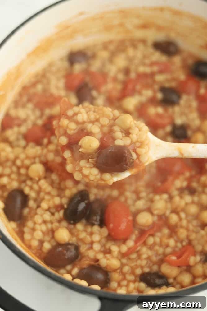 a spoon scooping up a serving of one pot Greek couscous