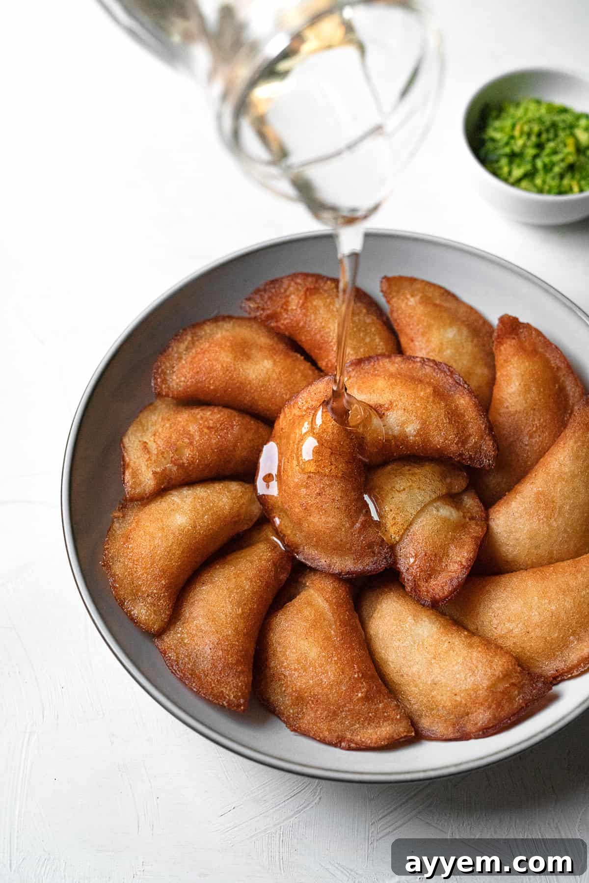 simple syrup being poured on atayef on platter 