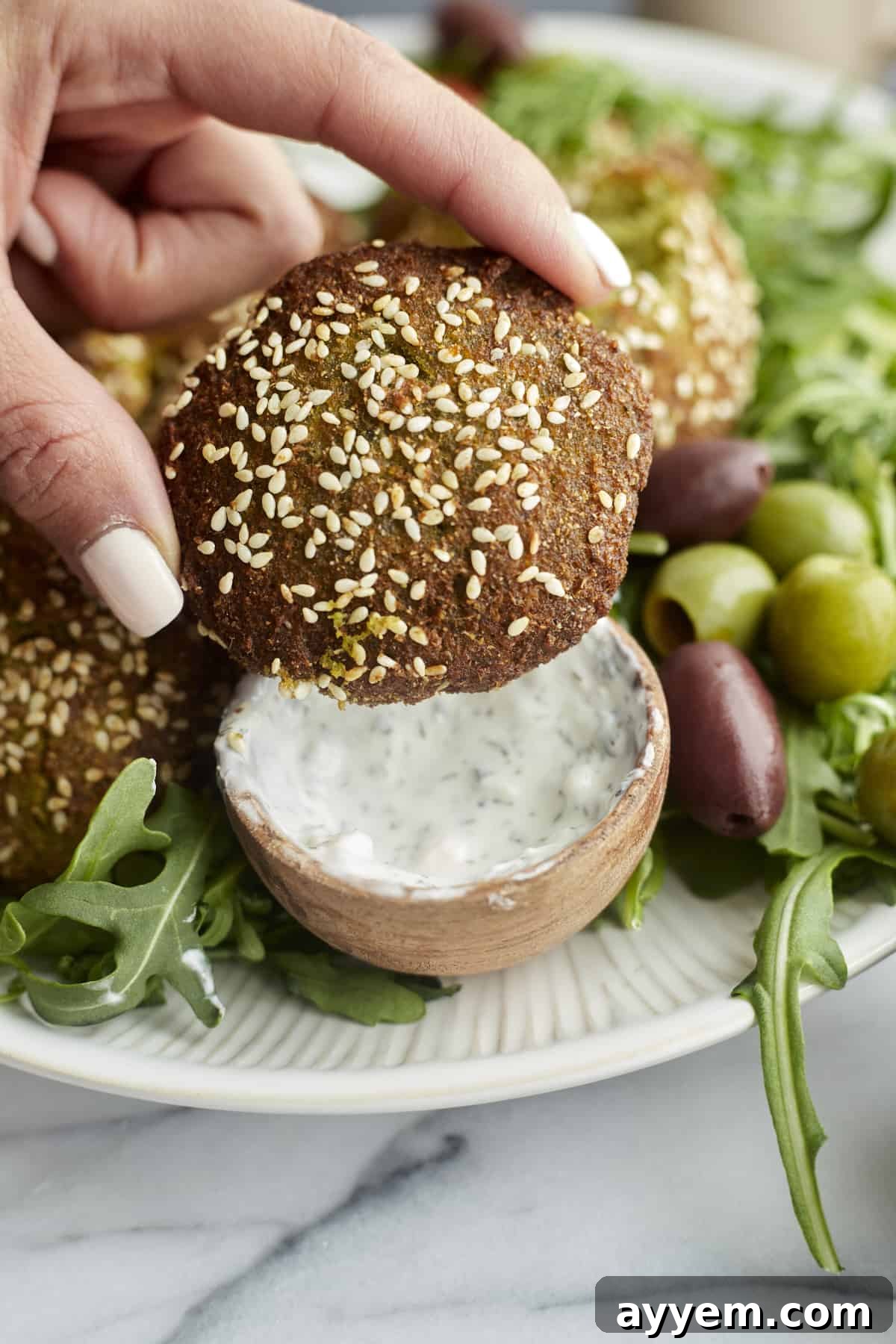 close up image of an air fryer falafel topped with sesame seeds.