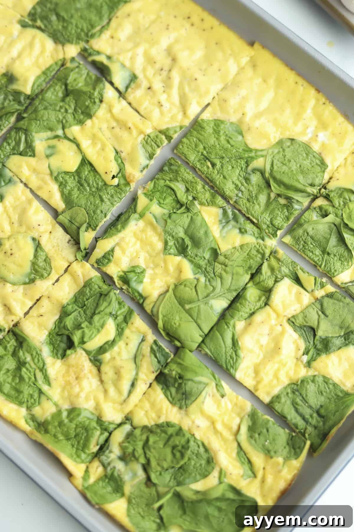 Golden-brown squares of baked eggs and spinach neatly arranged on a baking pan, showcasing their perfect texture, ready to be transformed into sandwiches.