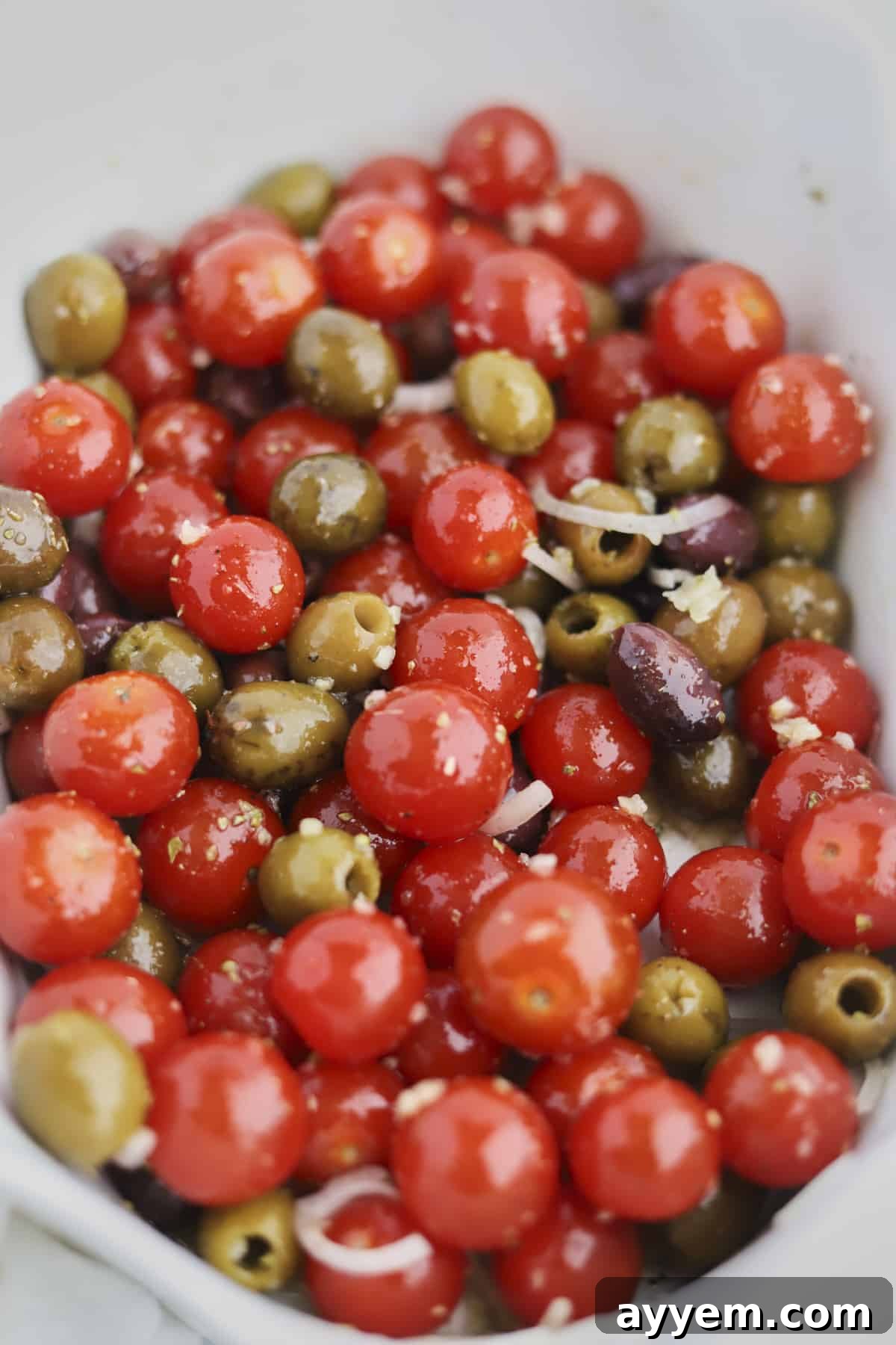Baking dish of tomatoes, olives, onions and olive oil before baking
