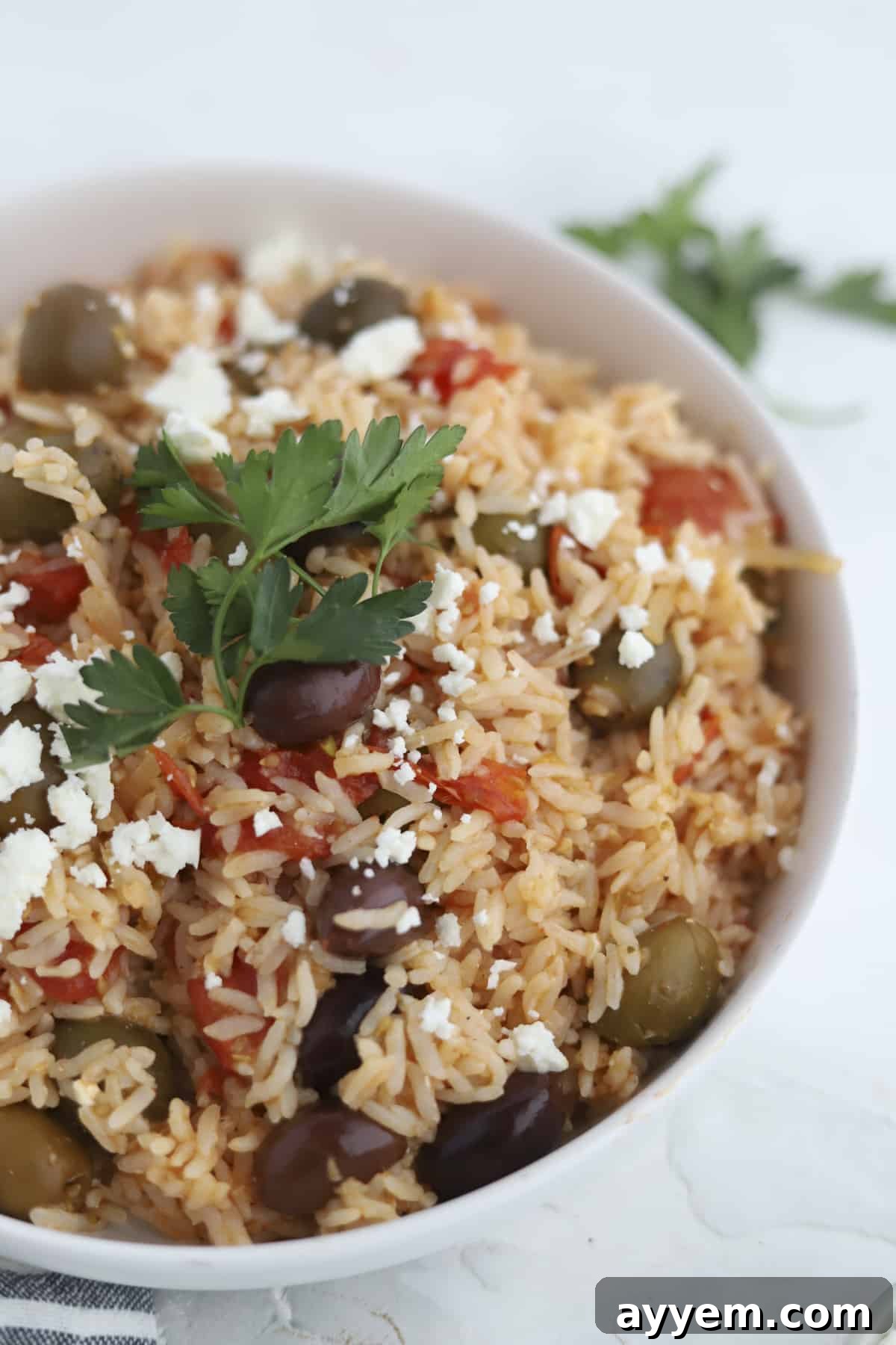 Closeup image of a bowl of Greek Rice Bake topped with feta and fresh herbs