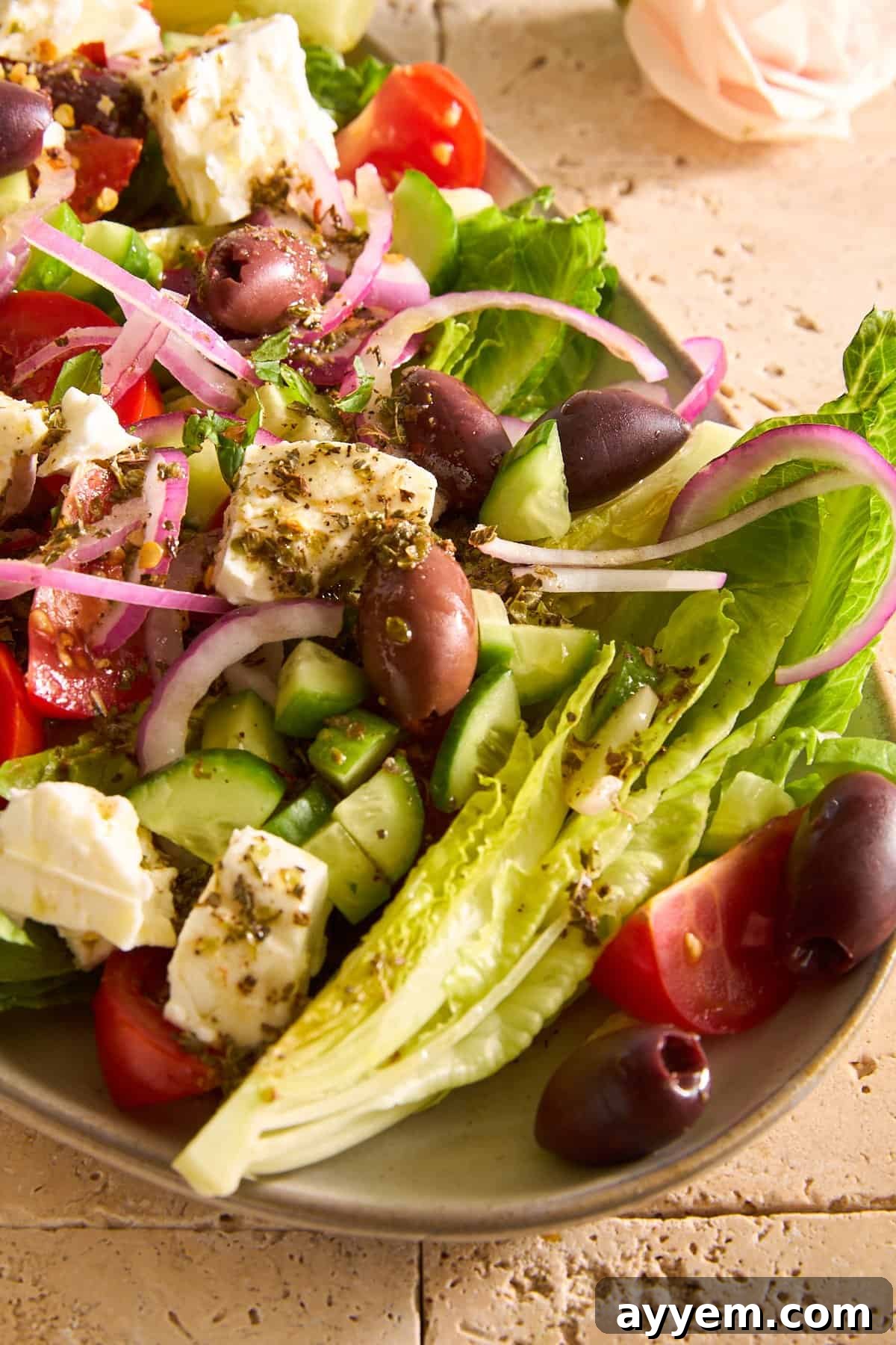 Prepared Greek Salad in a white bowl, drizzled with olive oil and herbs