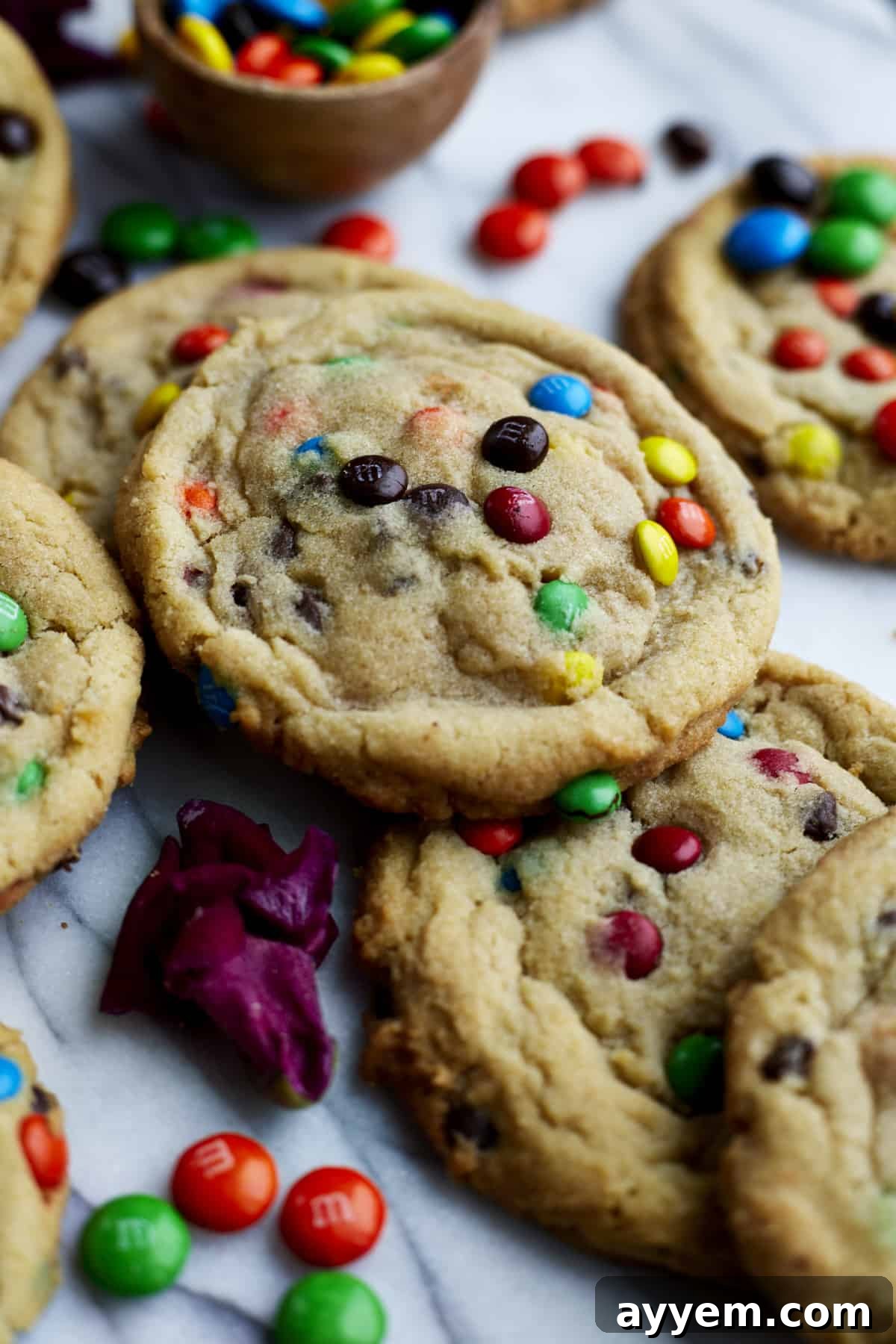 A hand reaching for a soft-baked M&M cookie, showcasing the perfect texture and inviting appeal.