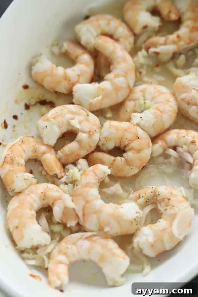 cooked lemon garlic shrimp in a white baking dish.