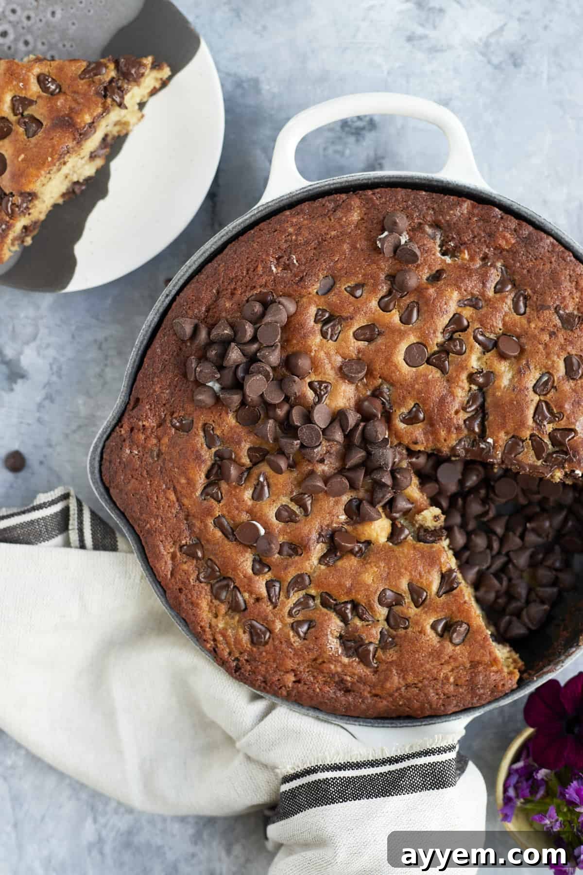 Close-up overhead view of the chocolate chip banana bread skillet, with a slice already removed and placed on a plate, showcasing the fluffy interior.