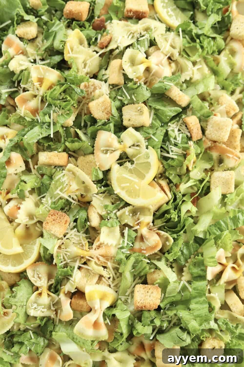 close up image of pesto pasta salad topped with lemon wedges
