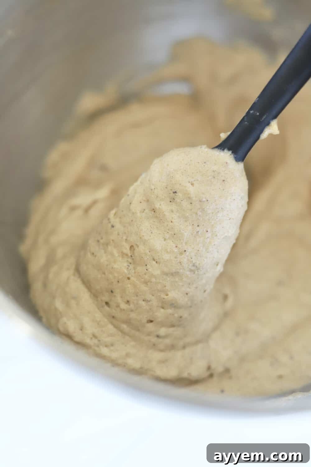 Rich, creamy brown butter toffee cookie dough on a plastic spoon, ready for baking