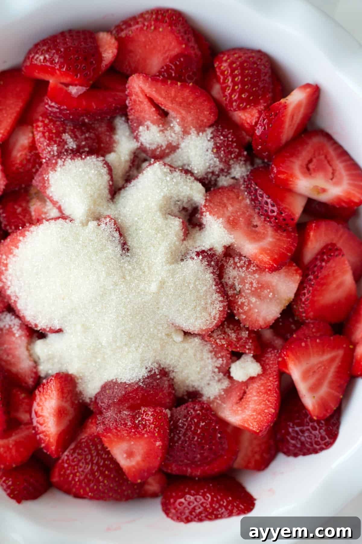 A bowl of fresh strawberries topped with sugar. 