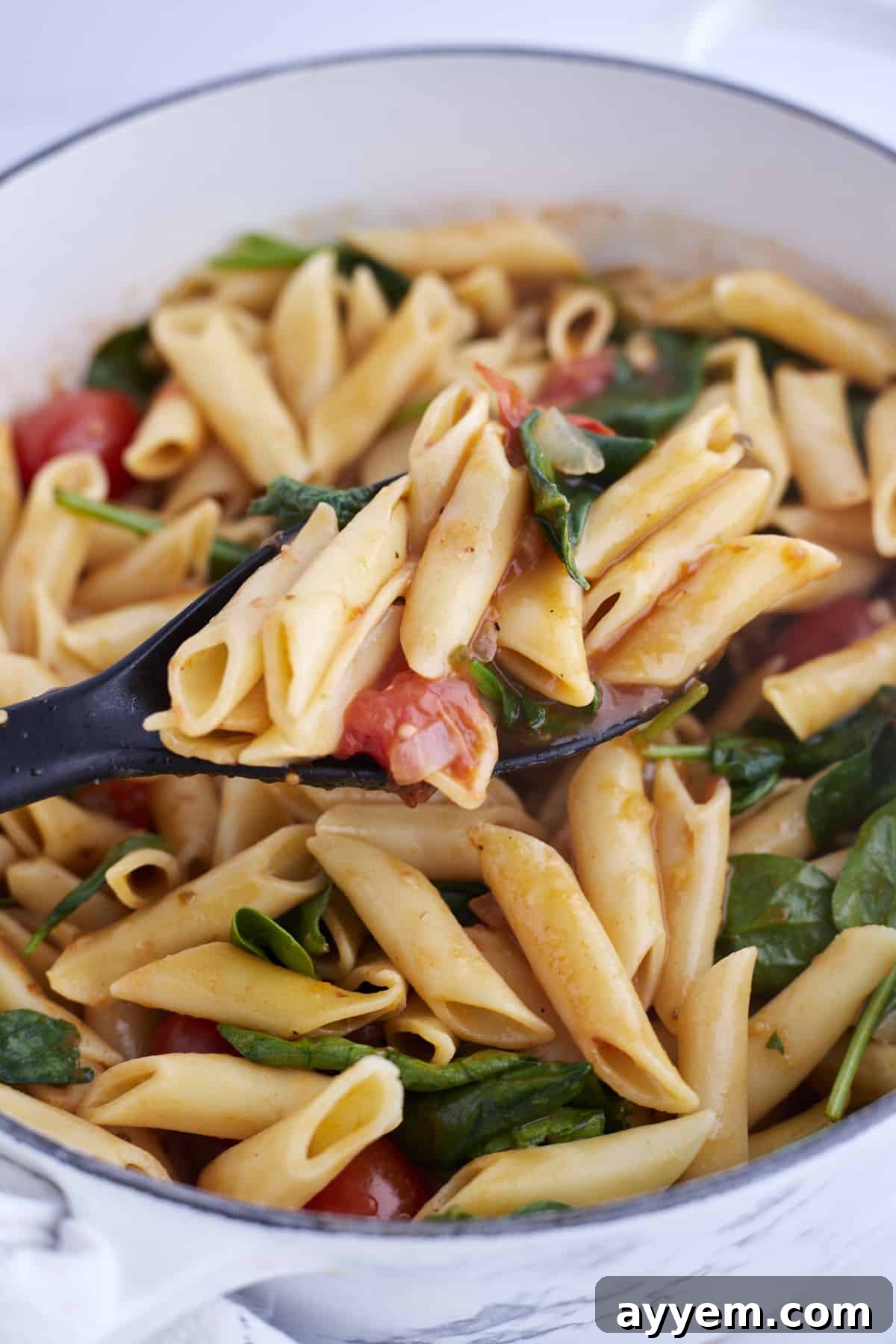 Close-up shot of a steaming pot of One-Pot Tomato Spinach Pasta, highlighting the vibrant colors and appealing texture.