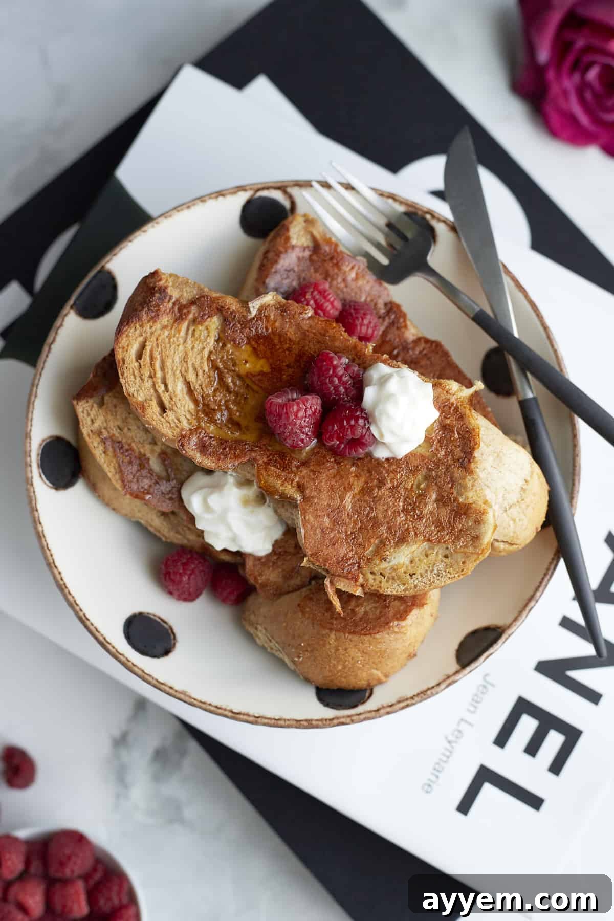 Plated Sheet Pan French Toast garnished with fresh raspberries and a dollop of whipped cream, ready to be enjoyed.