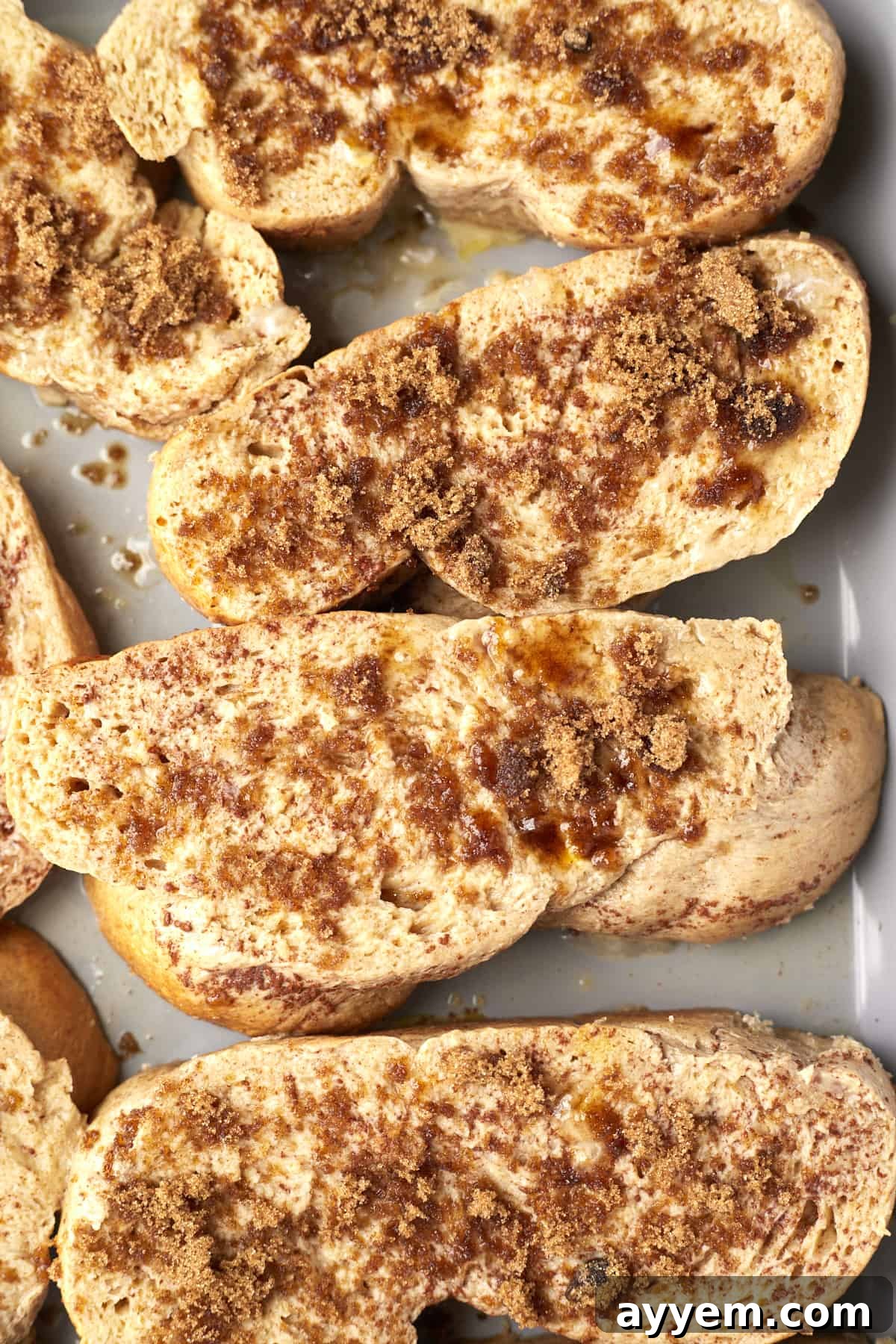 Close-up of Sheet Pan French Toast slices topped with a sprinkle of brown sugar, ready for the oven.