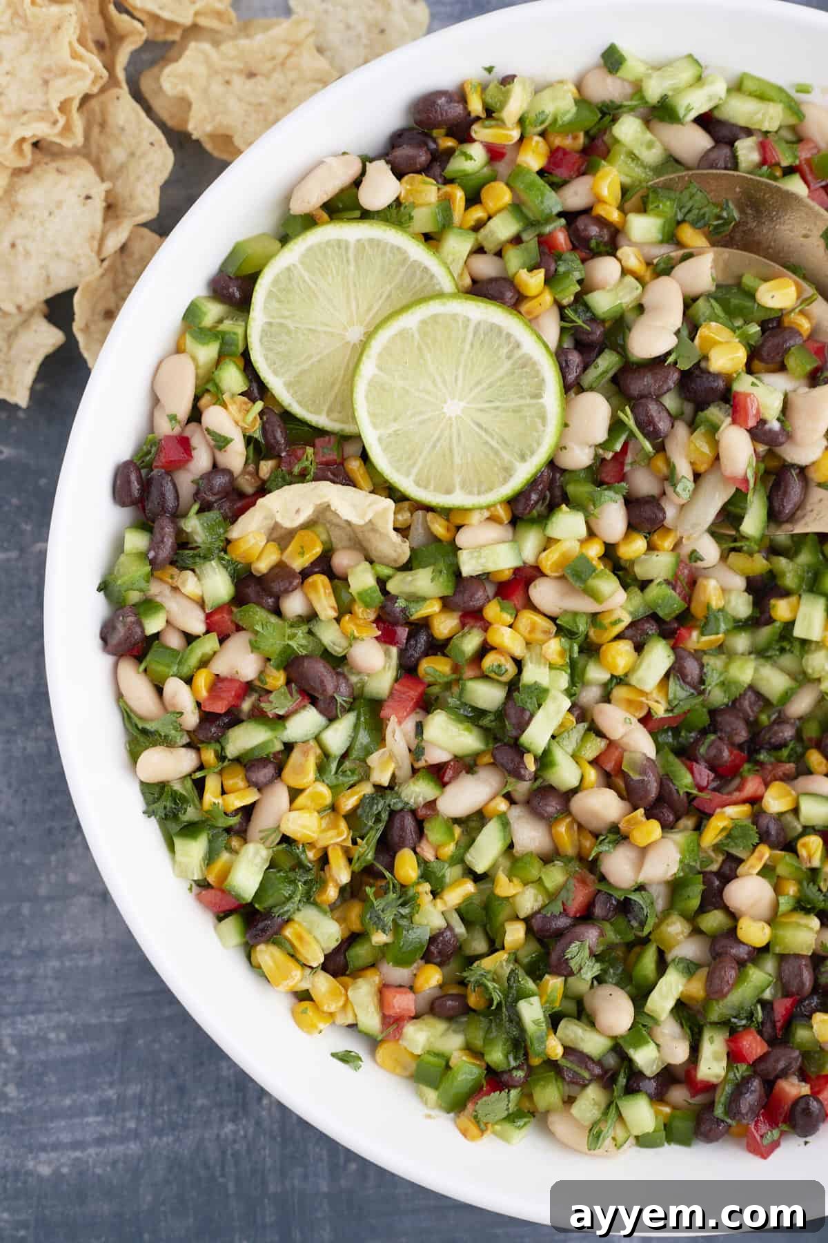Large white bowl with cowboy caviar, limes, and gold spring spoons