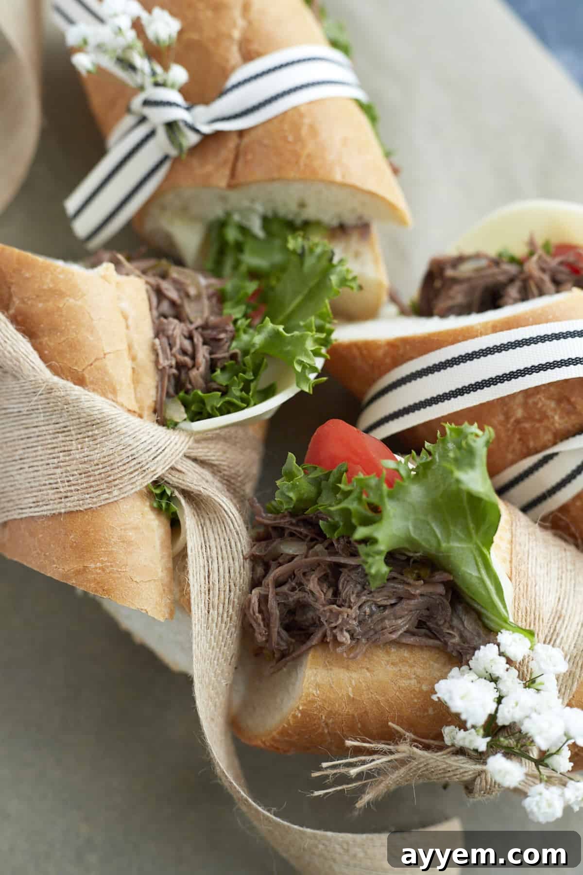 Multiple Po'Boy sandwiches, beautifully wrapped with ribbon and garnished with fresh lettuce, tomatoes, and cheese, ready for enjoyment.