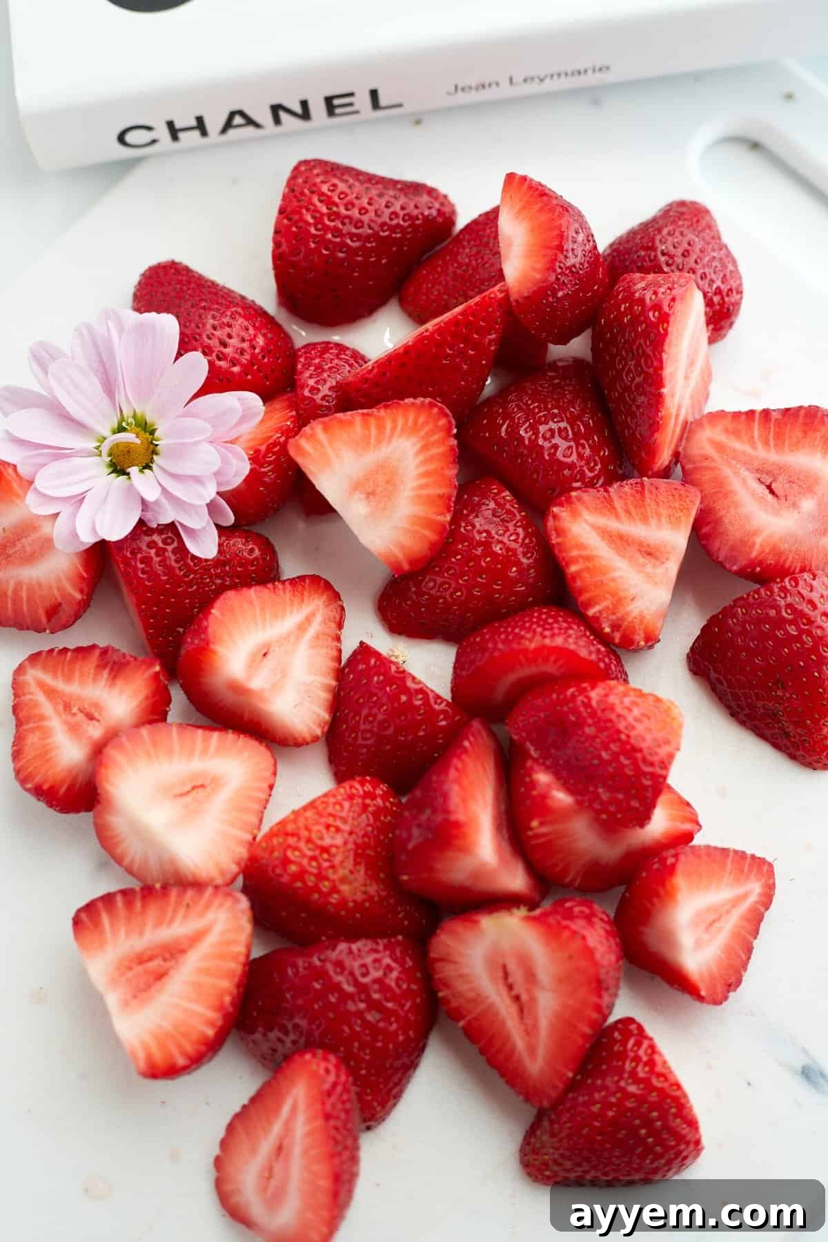 Chopped strawberries with a small flower on a cutting board