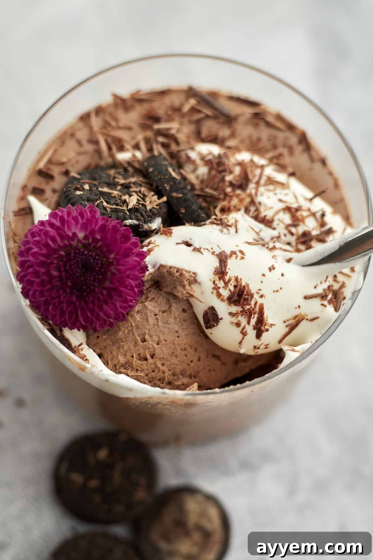 oreo chocolate mousse in one ramekin with spoon, garnished with whipped cream, chocolate, and oreo cookies. 
