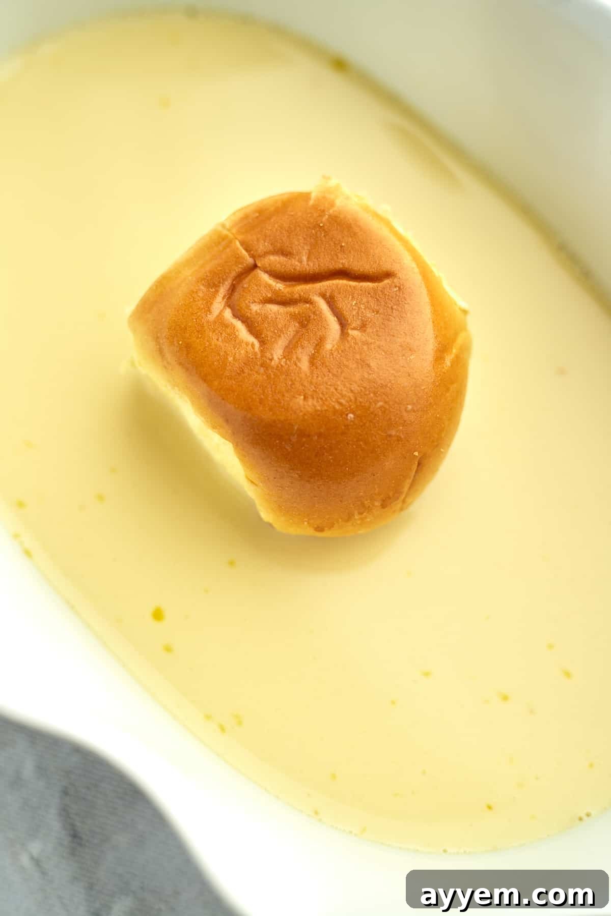 a brioche bun sitting in an egg mixture for french toast